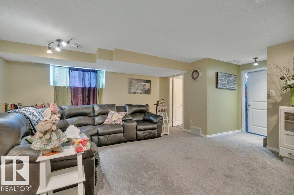 Spacious carpeted room featuring track lighting and a window - 6042 214 Street, Edmonton, AB - Indoor