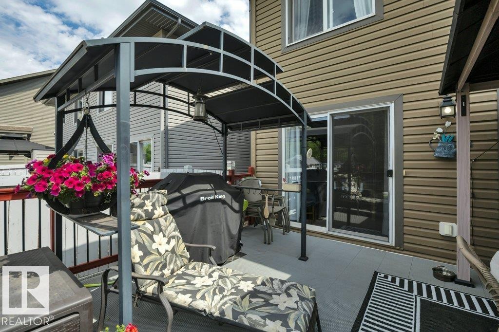 Expansive outdoor deck featuring a covered pergola structure, durable railing, and direct access to interior via sliding glass door - 6042 214 Street, Edmonton, AB - Outdoor With Deck Patio Veranda