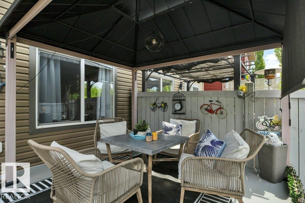 Covered patio area featuring a dark metal gazebo, a privacy fence, and horizontal siding - 6042 214 Street, Edmonton, AB - Outdoor With Deck Patio Veranda With Exterior