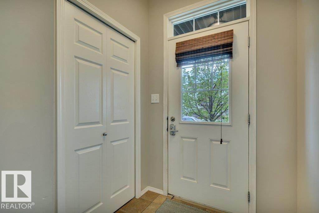 Entryway featuring a paneled door with a transom window, bi-fold closet doors, and tile flooring - 6042 214 Street, Edmonton, AB - Indoor Photo Showing Other Room