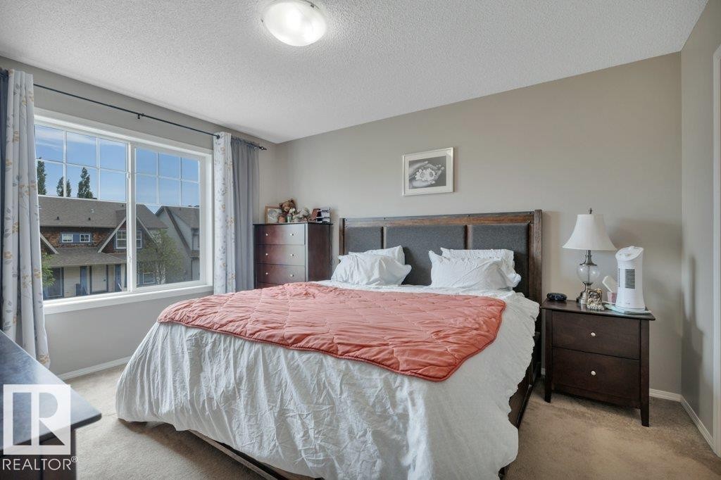 Carpeted bedroom with neutral wall paint and a large window featuring white framing - 6042 214 Street, Edmonton, AB - Indoor Photo Showing Bedroom