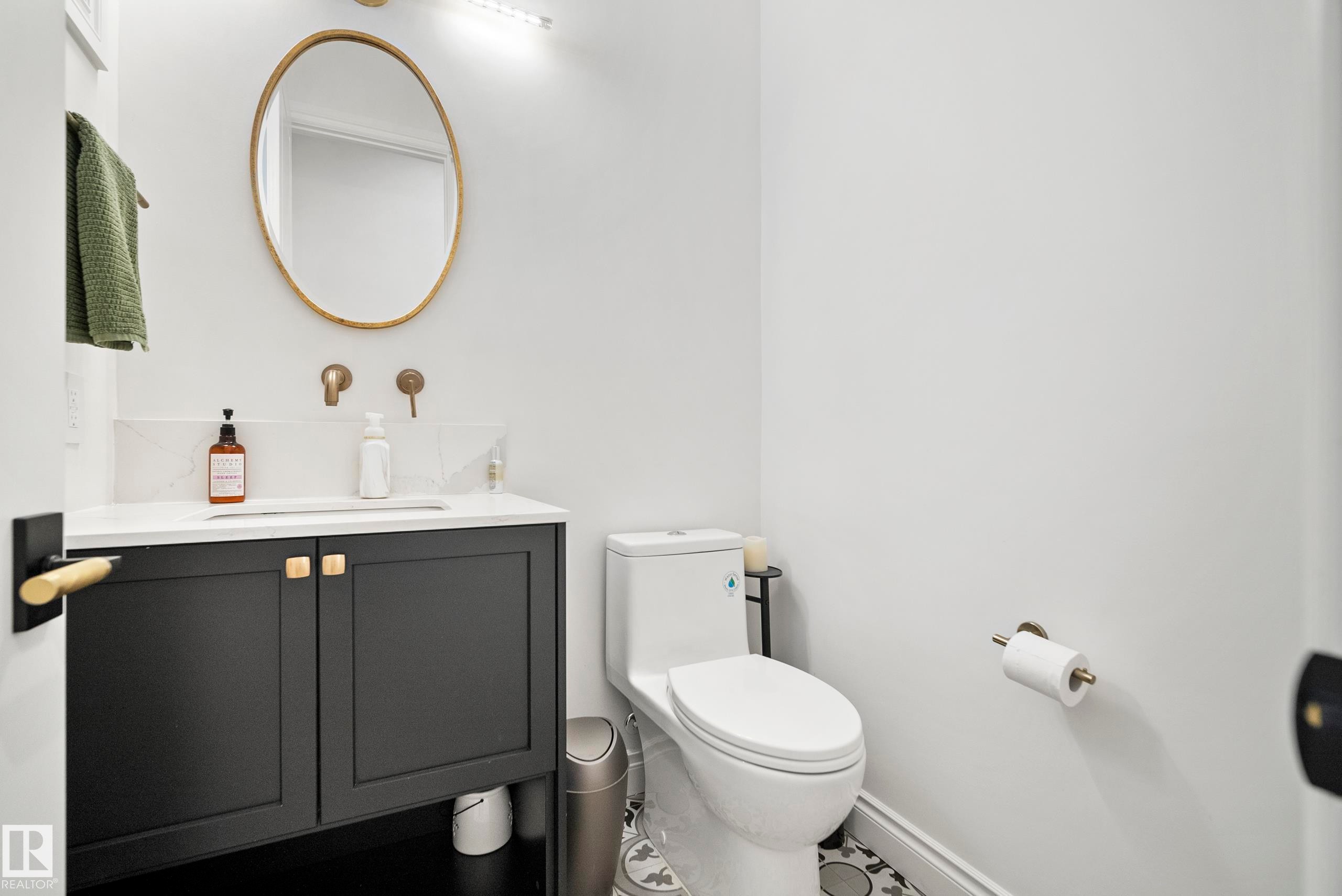 Bathroom featuring a matte black vanity with gold-tone hardware, white countertop, and gold-tone wall-mounted faucet - 6115 111 Avenue, Edmonton, AB - Indoor Photo Showing Bathroom