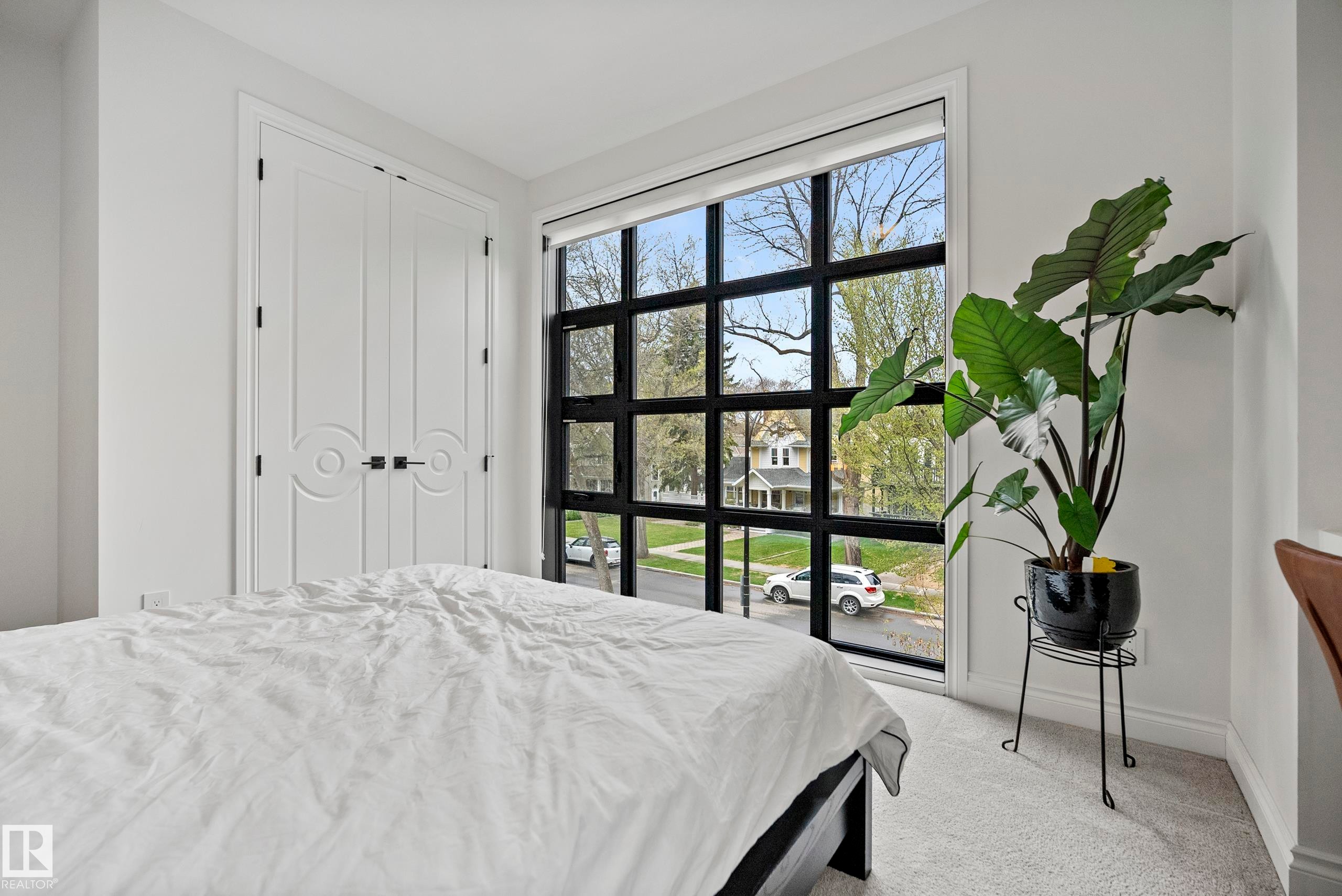 Grid-pattern window with black framing, light gray wall-to-wall carpeting, and white walls - 6115 111 Avenue, Edmonton, AB - Indoor Photo Showing Bedroom