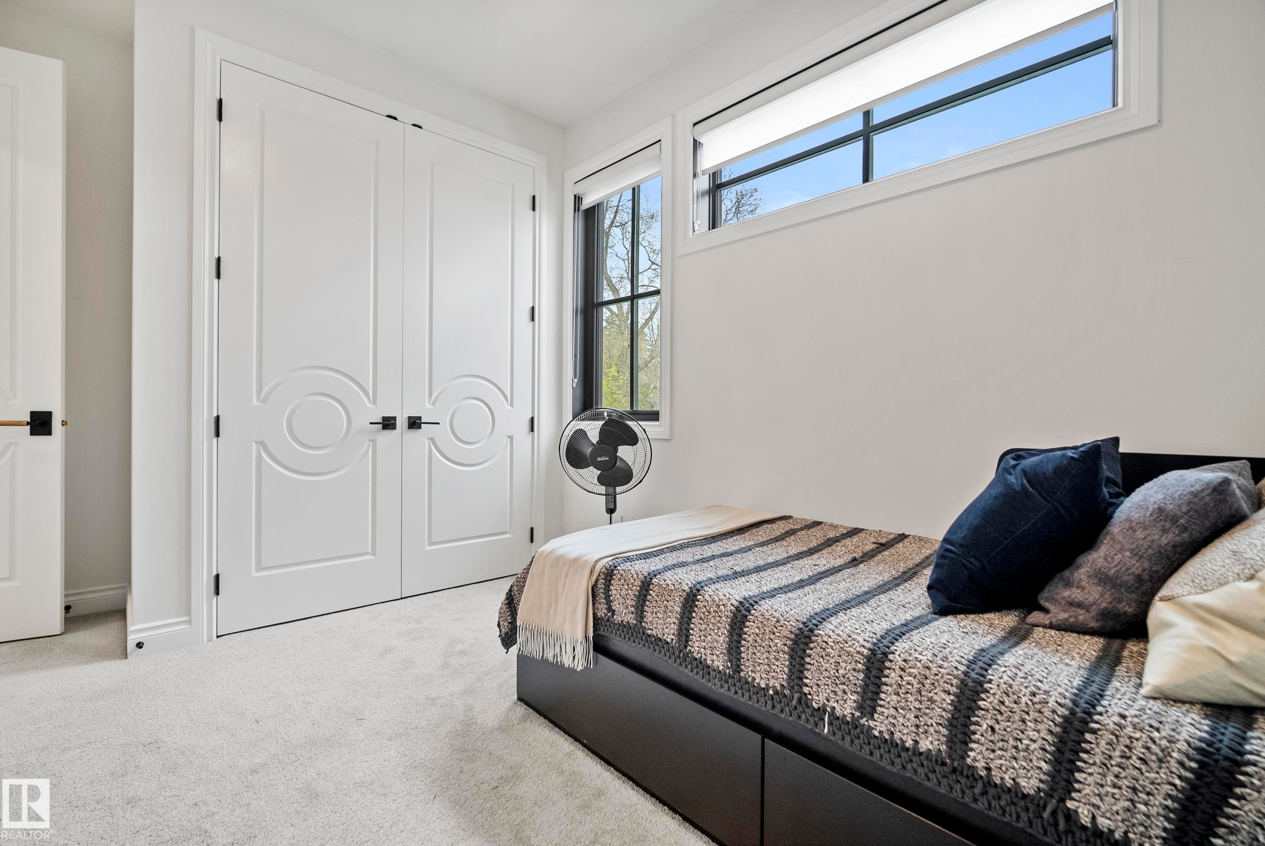 Bright room featuring a large window with black framing, a transom window, and white trim - 6115 111 Avenue, Edmonton, AB - Indoor Photo Showing Bedroom