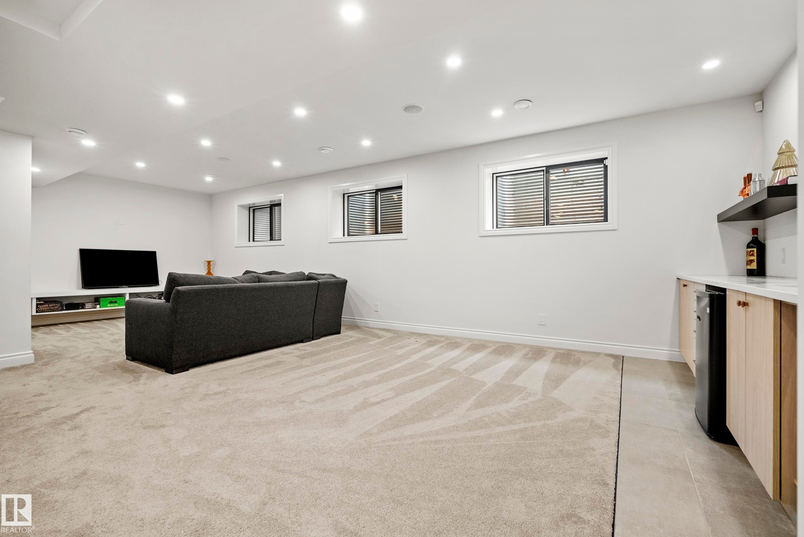 Spacious lower-level entertainment area featuring recessed lighting, light-toned carpeting, and multiple windows - 6115 111 Avenue, Edmonton, AB - Indoor