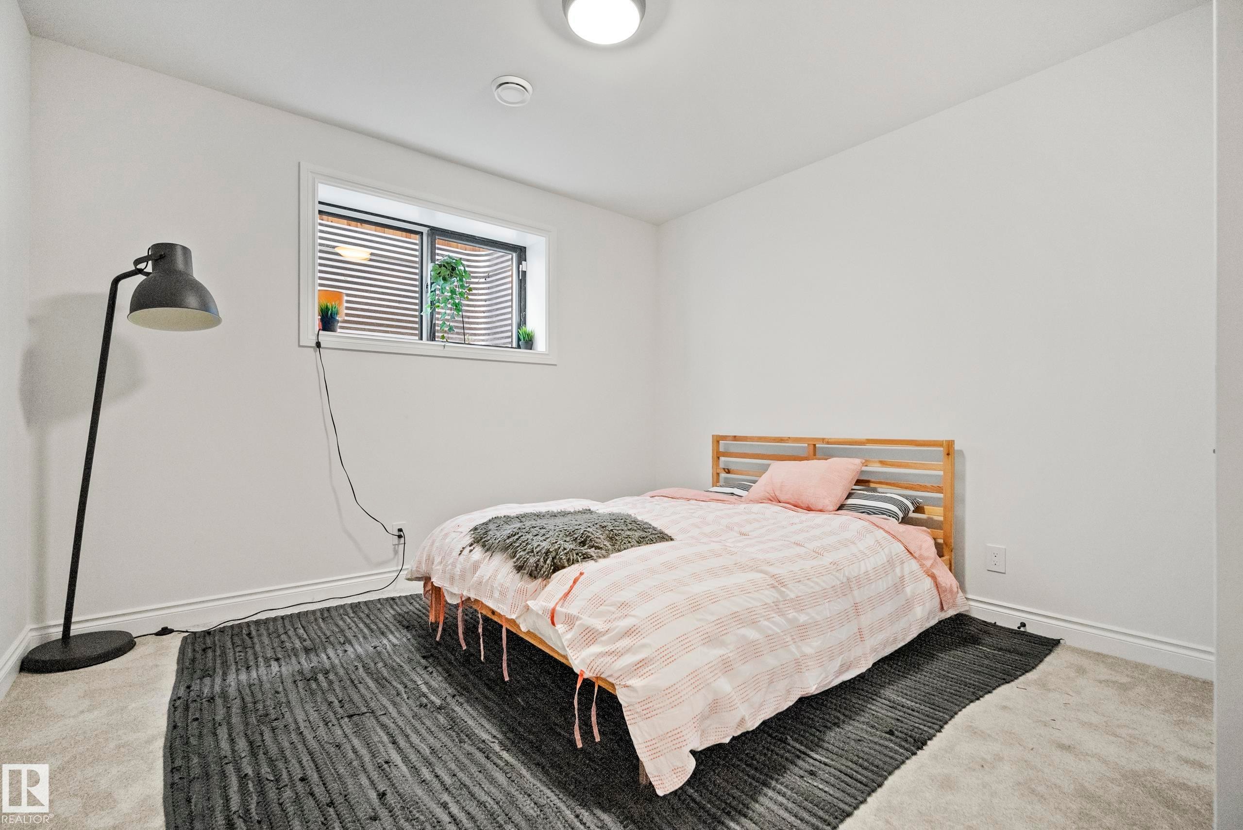 Carpeted room with a single window featuring horizontal blinds and a window well - 6115 111 Avenue, Edmonton, AB - Indoor Photo Showing Bedroom