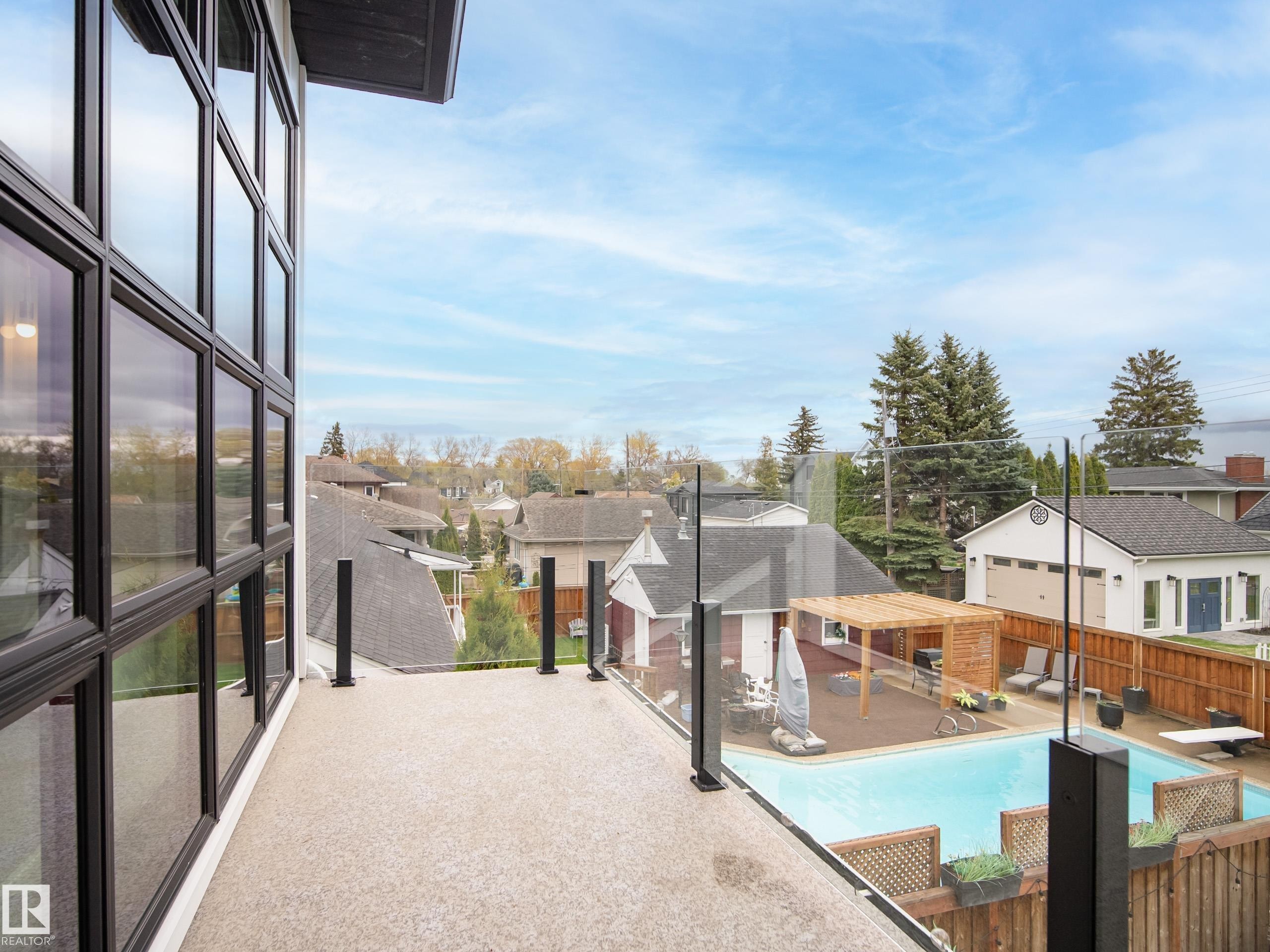 Balcony featuring a glass railing system, textured flooring, and a multi-pane window wall - 6115 111 Avenue, Edmonton, AB - Outdoor