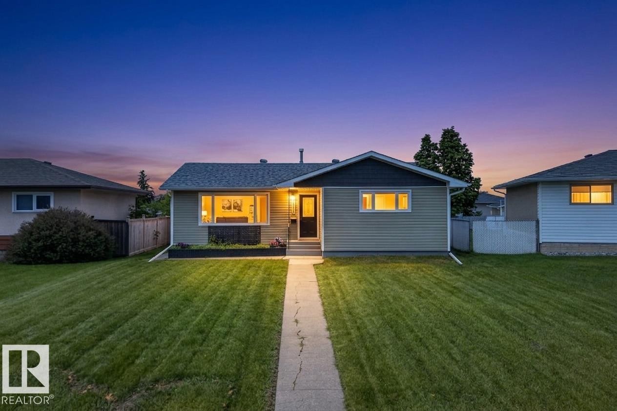 Ranch-style exterior featuring light green siding, a dark pitched roof, and a front-facing window box - 14128 73 Street, Edmonton, AB