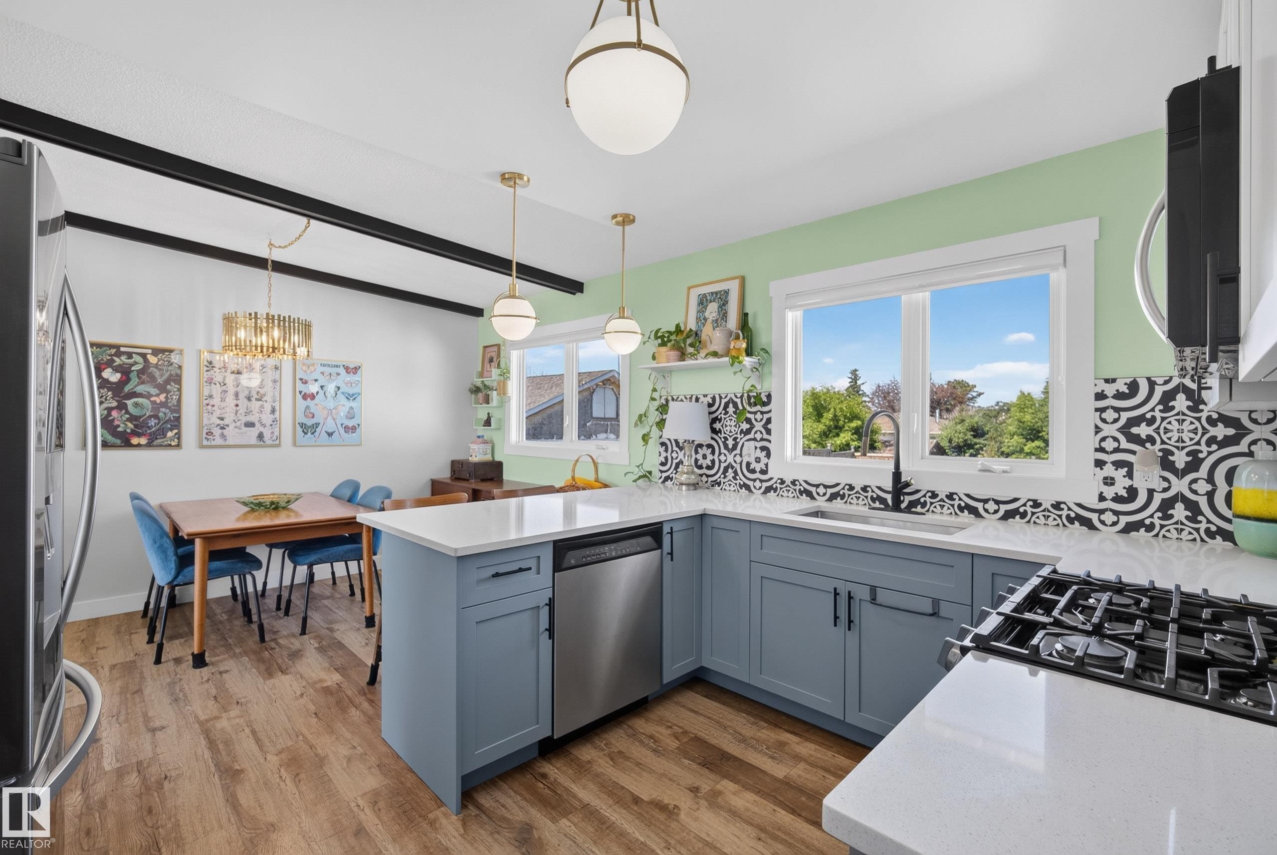 Open-concept kitchen with wood-finish flooring, light blue cabinetry, and white countertops - 14128 73 Street, Edmonton, AB