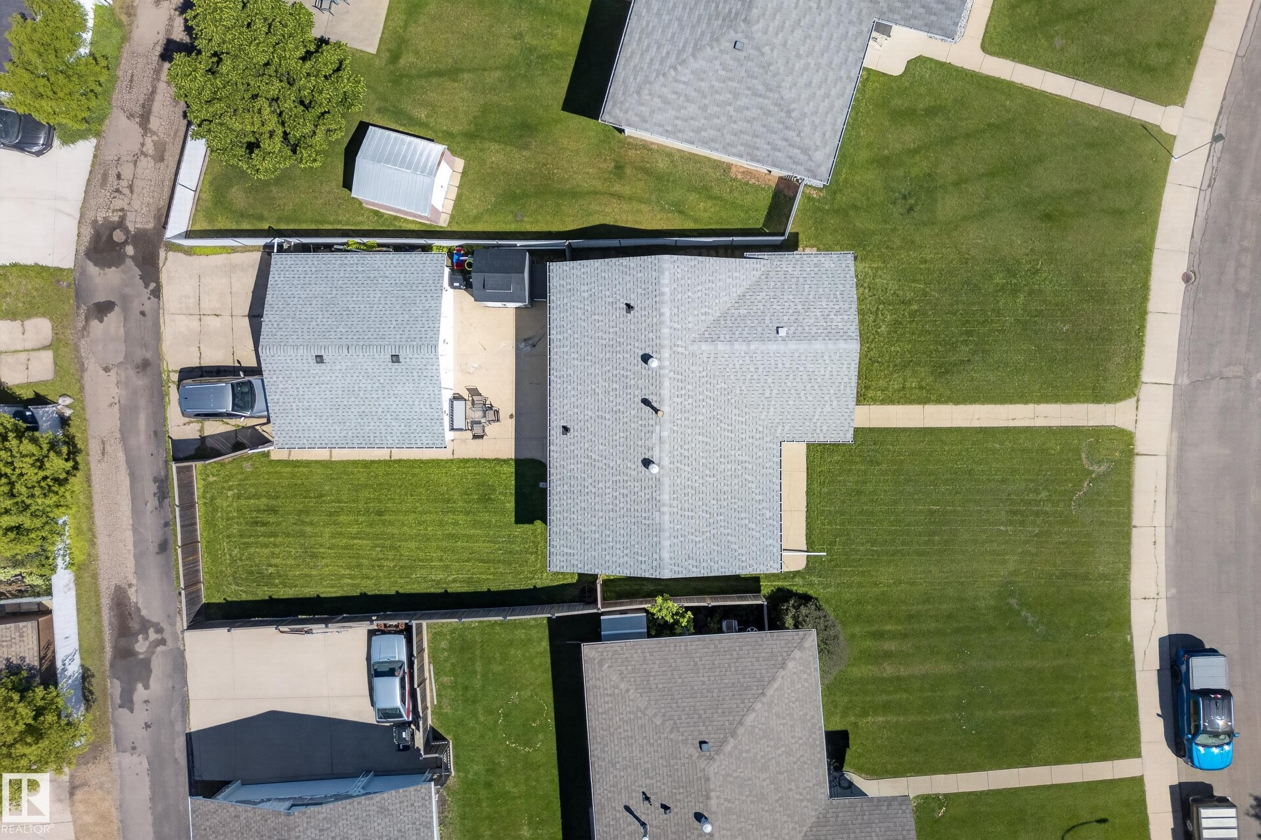 Aerial view showcasing a residential property with a shingle roof and an extensive concrete patio - 14128 73 Street, Edmonton, AB
