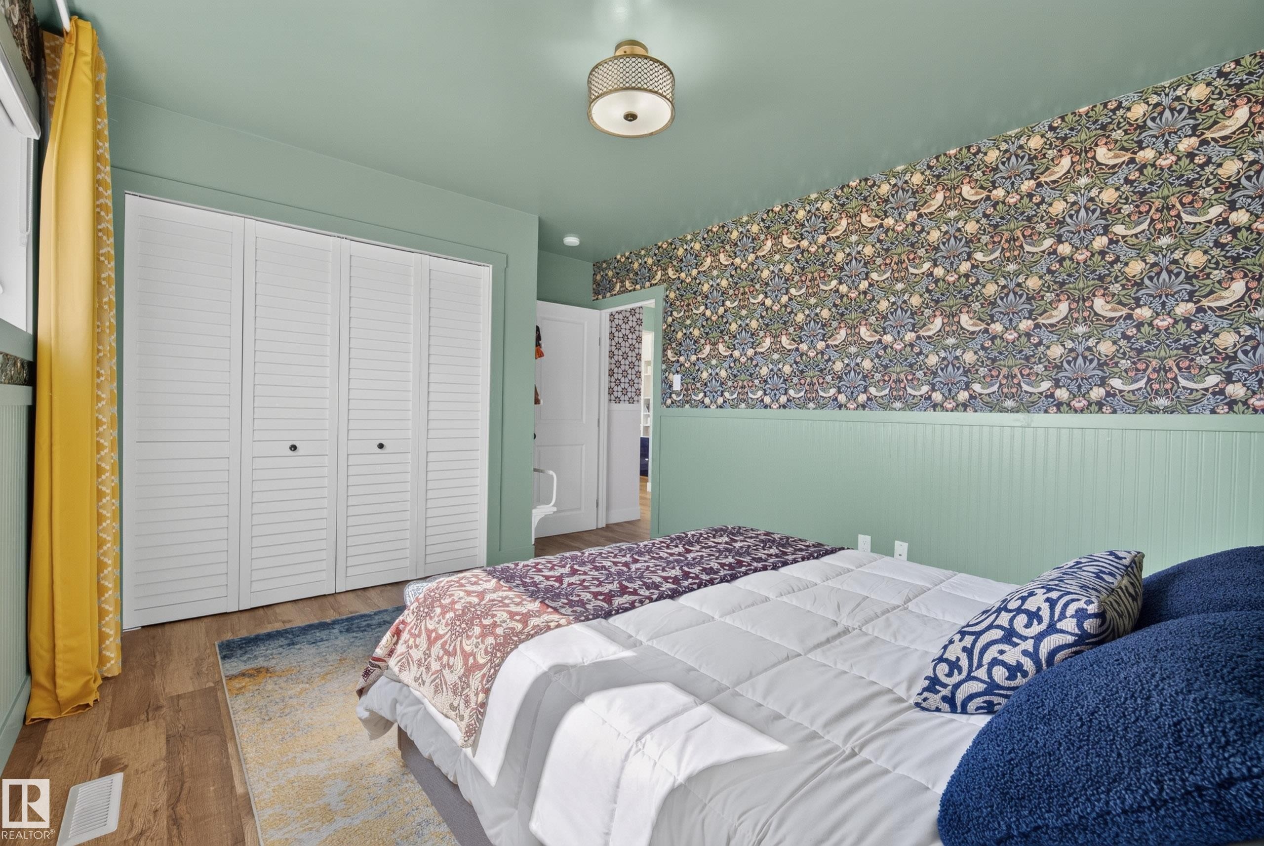 Bedroom featuring wood-finish flooring, a decorative ceiling fixture, and bi-fold louvered closet doors - 14128 73 Street, Edmonton, AB