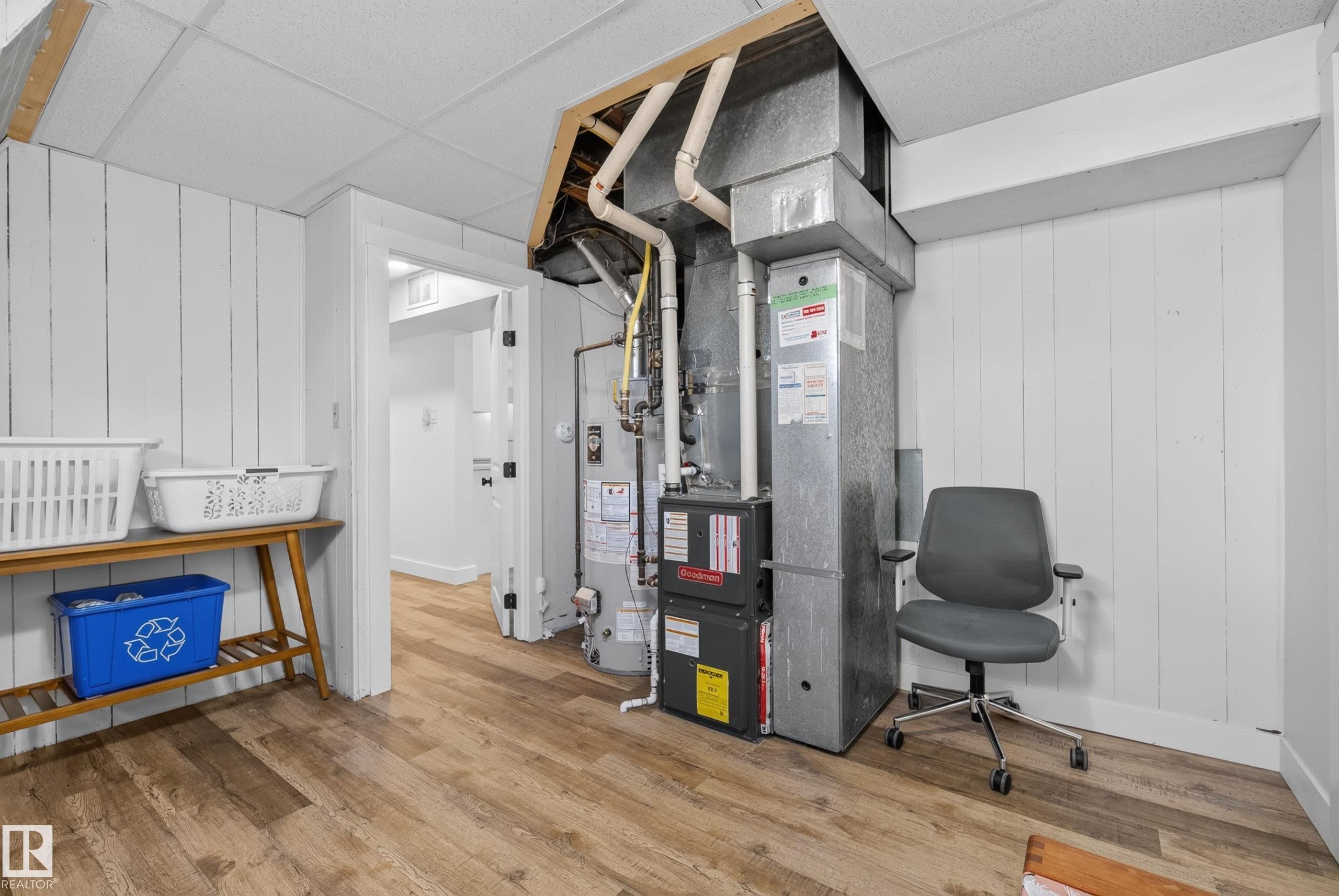 Utility area featuring plank-style wall paneling, wood-finish flooring, drop ceiling, and exposed ductwork - 14128 73 Street, Edmonton, AB