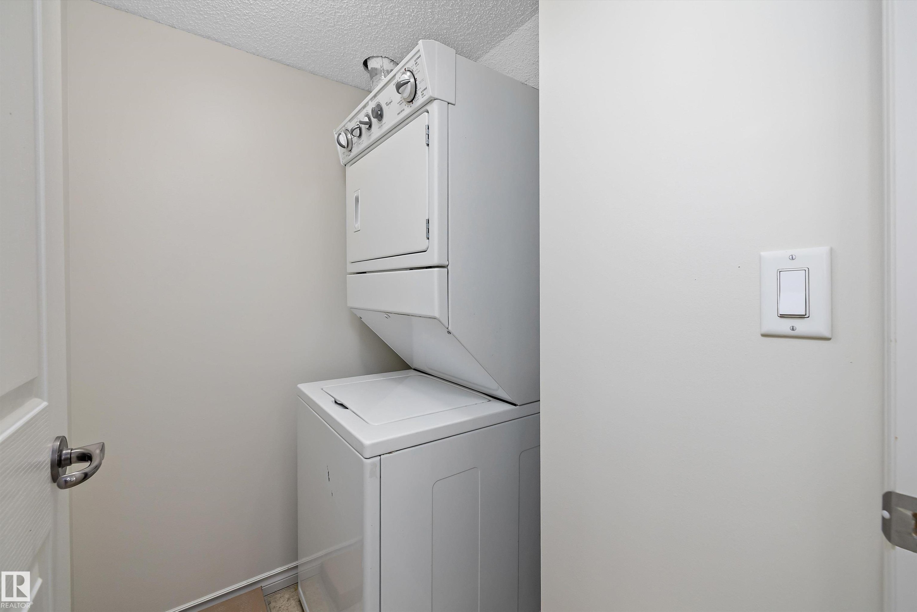 Dedicated laundry area featuring a stacked washer and dryer unit - 101 13825 155 Avenue, Edmonton, AB