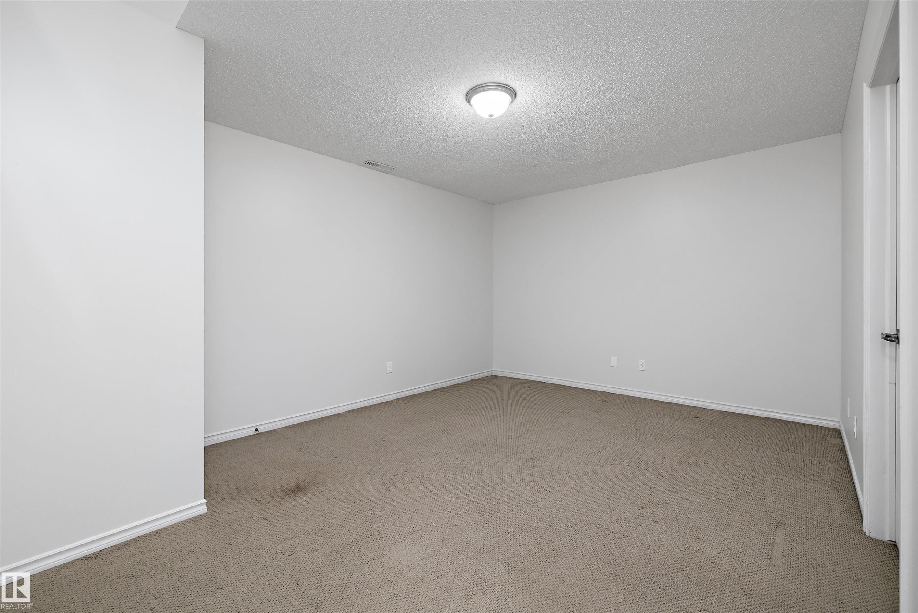 Neutral wall tones with a textured ceiling and flush mount lighting - 101 13825 155 Avenue, Edmonton, AB
