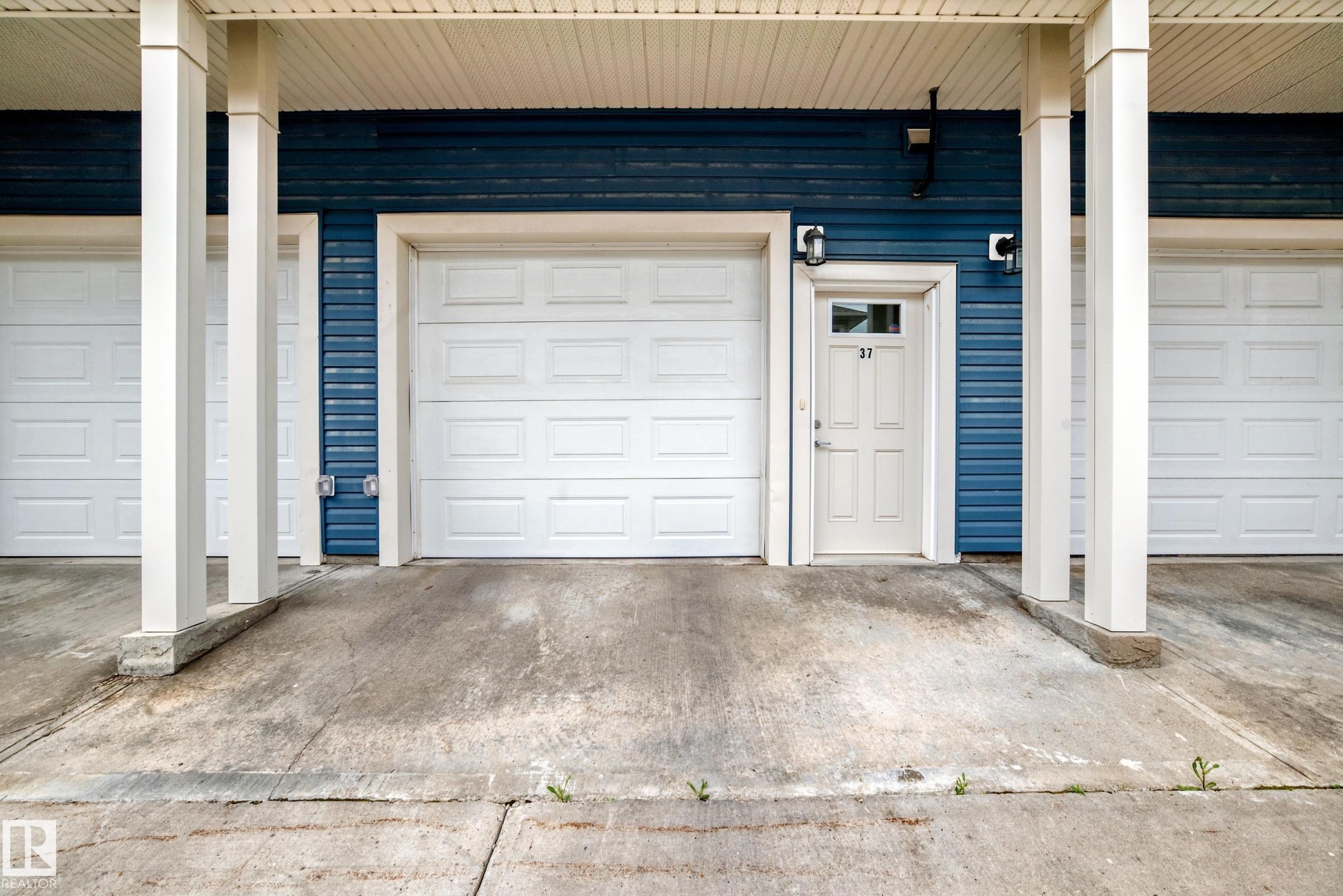 Exterior entrance featuring blue horizontal siding and white trim - 37 13003 132 Avenue Nw, Edmonton, AB