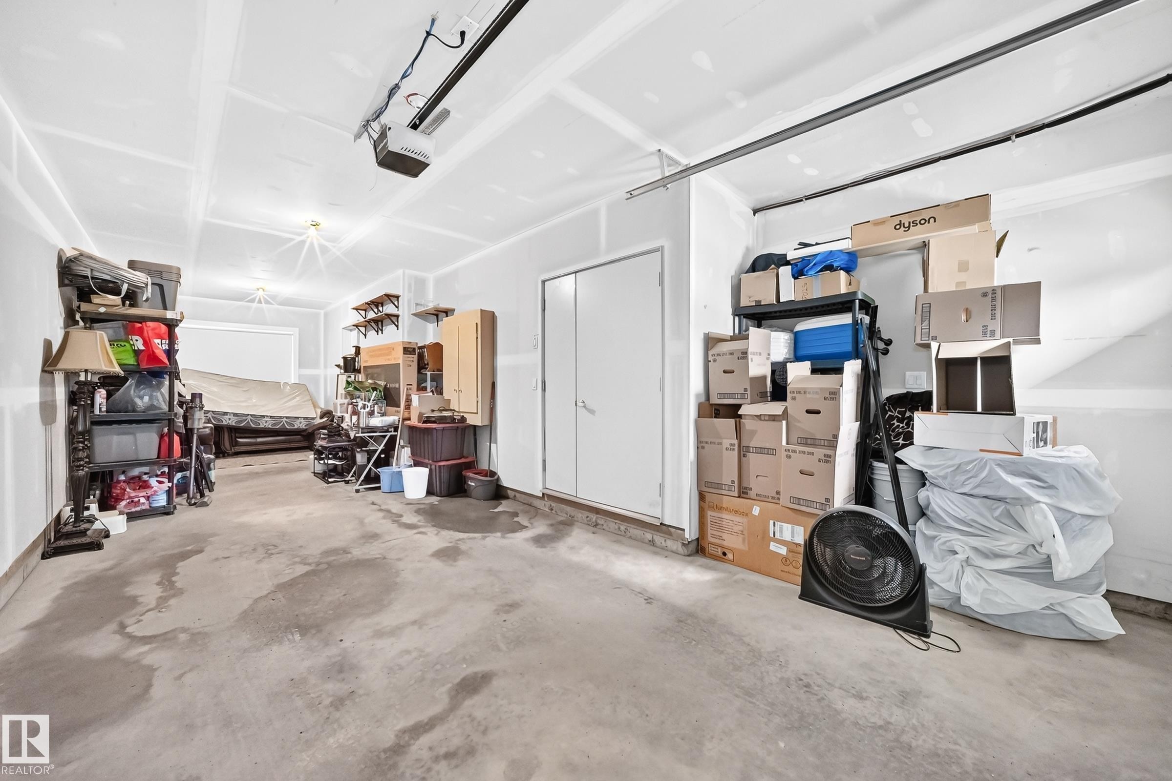 Two-car garage featuring a concrete floor, painted drywall, and an overhead garage door opener - 37 13003 132 Avenue Nw, Edmonton, AB