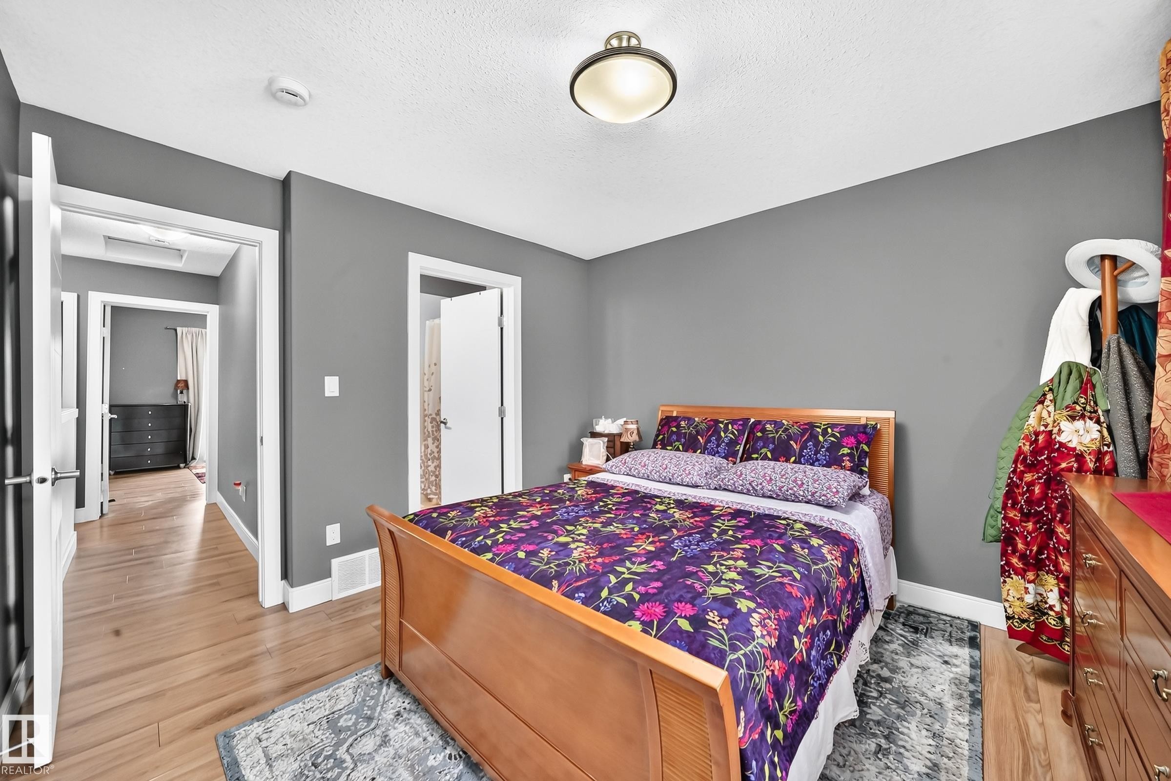 Bedroom featuring hardwood-finish flooring, neutral gray wall tones, and white trim - 37 13003 132 Avenue Nw, Edmonton, AB