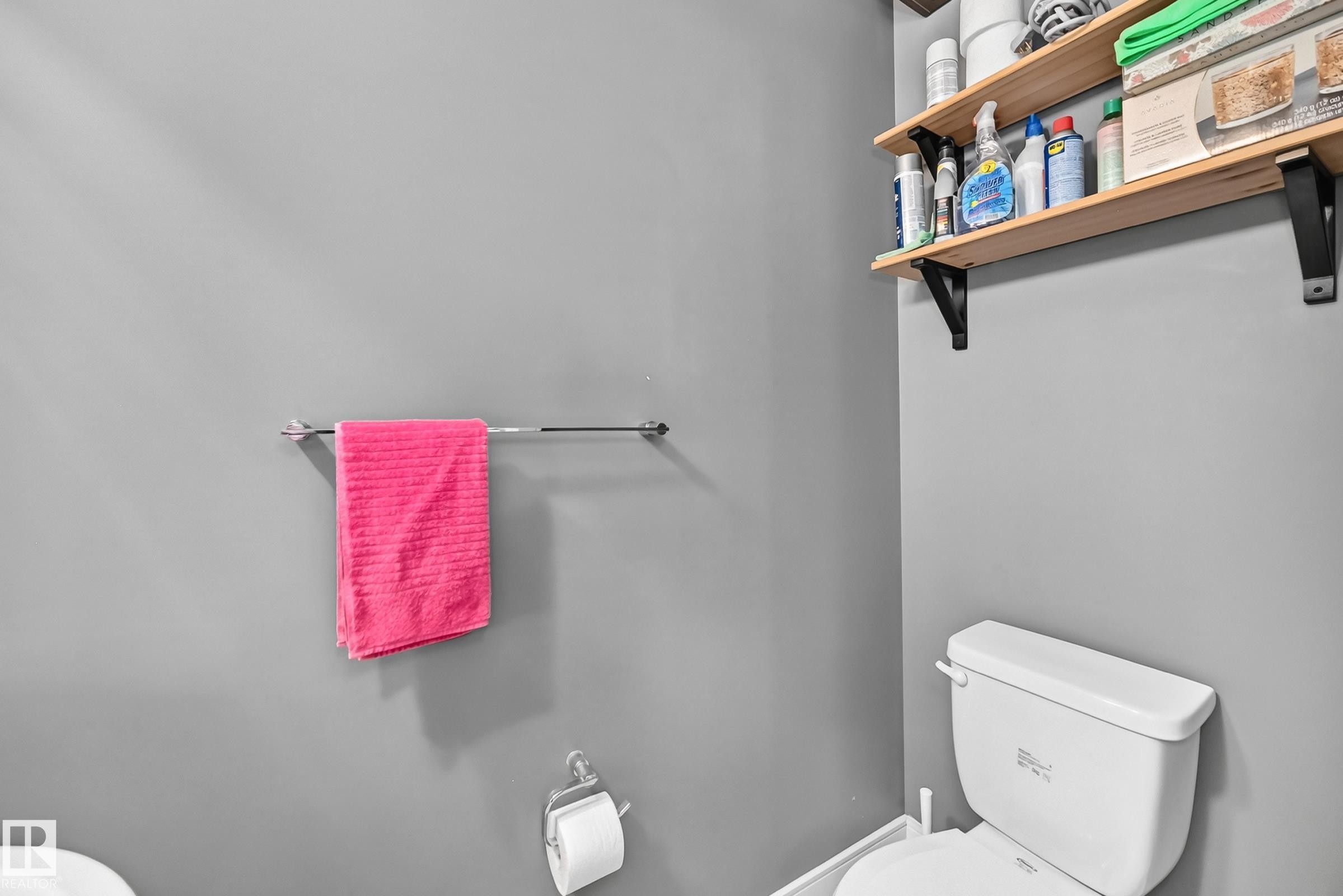 White toilet with chrome flush handle, light grey wall finish, and two wood-finish floating shelves with black brackets - 37 13003 132 Avenue Nw, Edmonton, AB