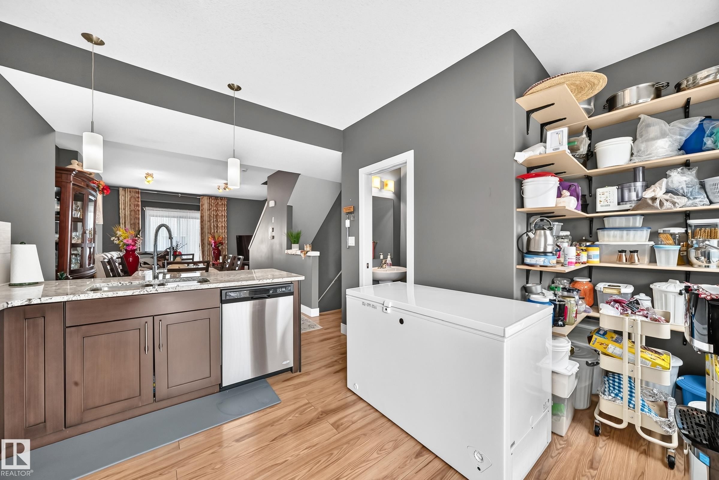Kitchen island with a granite-style countertop, undermount sink, and stainless steel dishwasher - 37 13003 132 Avenue Nw, Edmonton, AB