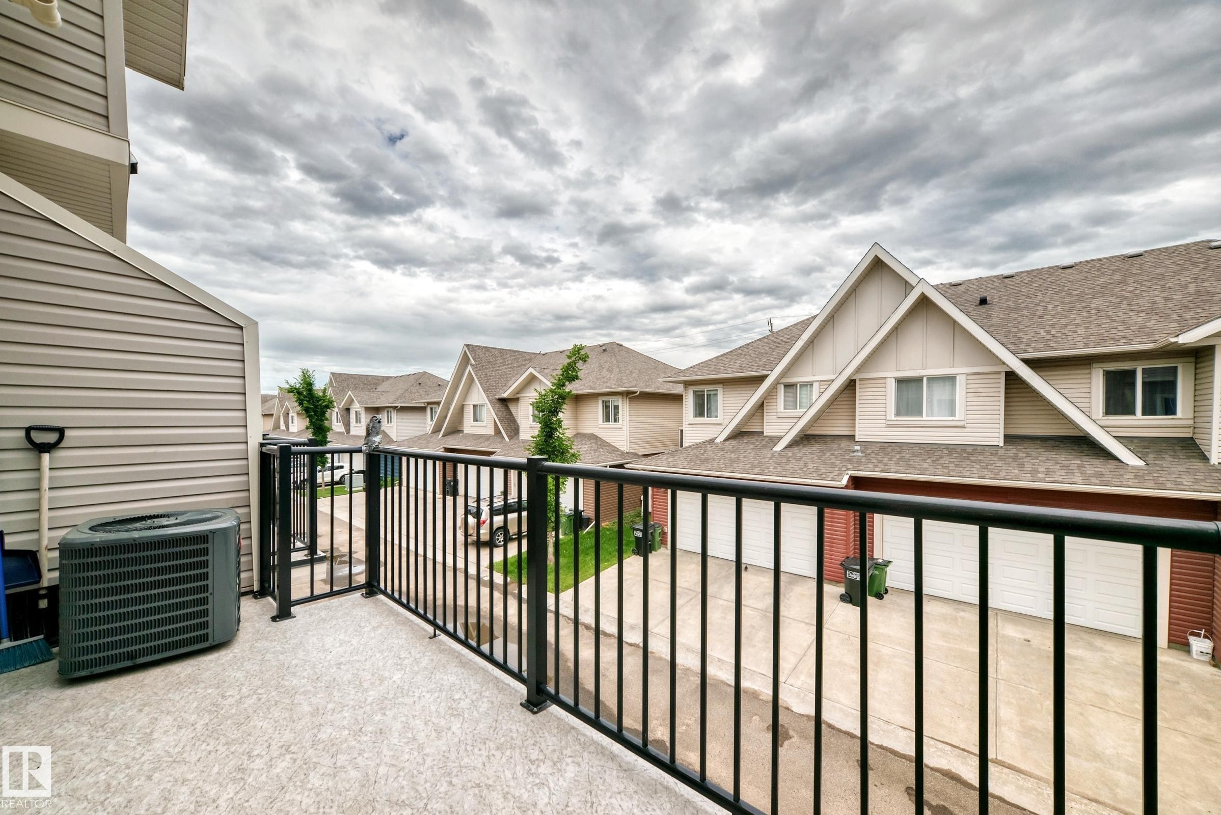 Upper-level balcony featuring textured flooring and a black metal railing - 37 13003 132 Avenue Nw, Edmonton, AB