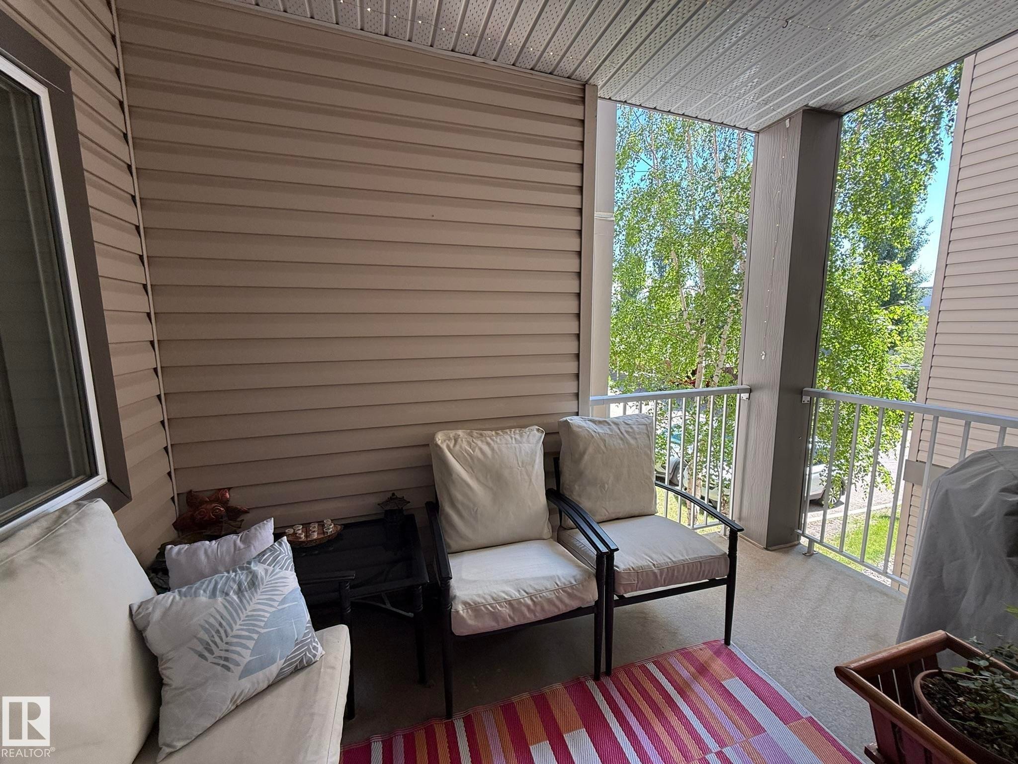 Covered balcony featuring neutral-toned siding and a white railing - 205 3425 19 Street, Edmonton, AB