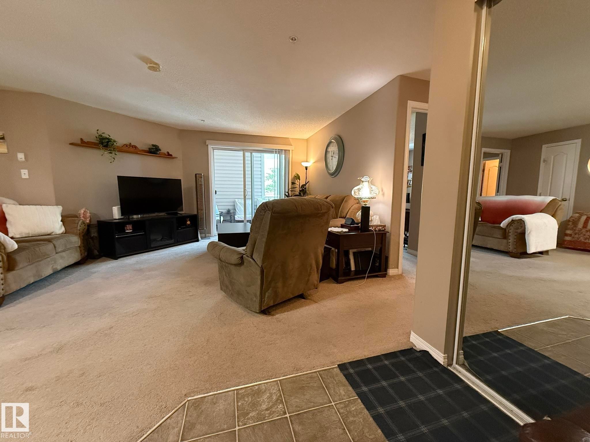 Open living space featuring neutral carpet flooring and a sliding glass door - 205 3425 19 Street, Edmonton, AB
