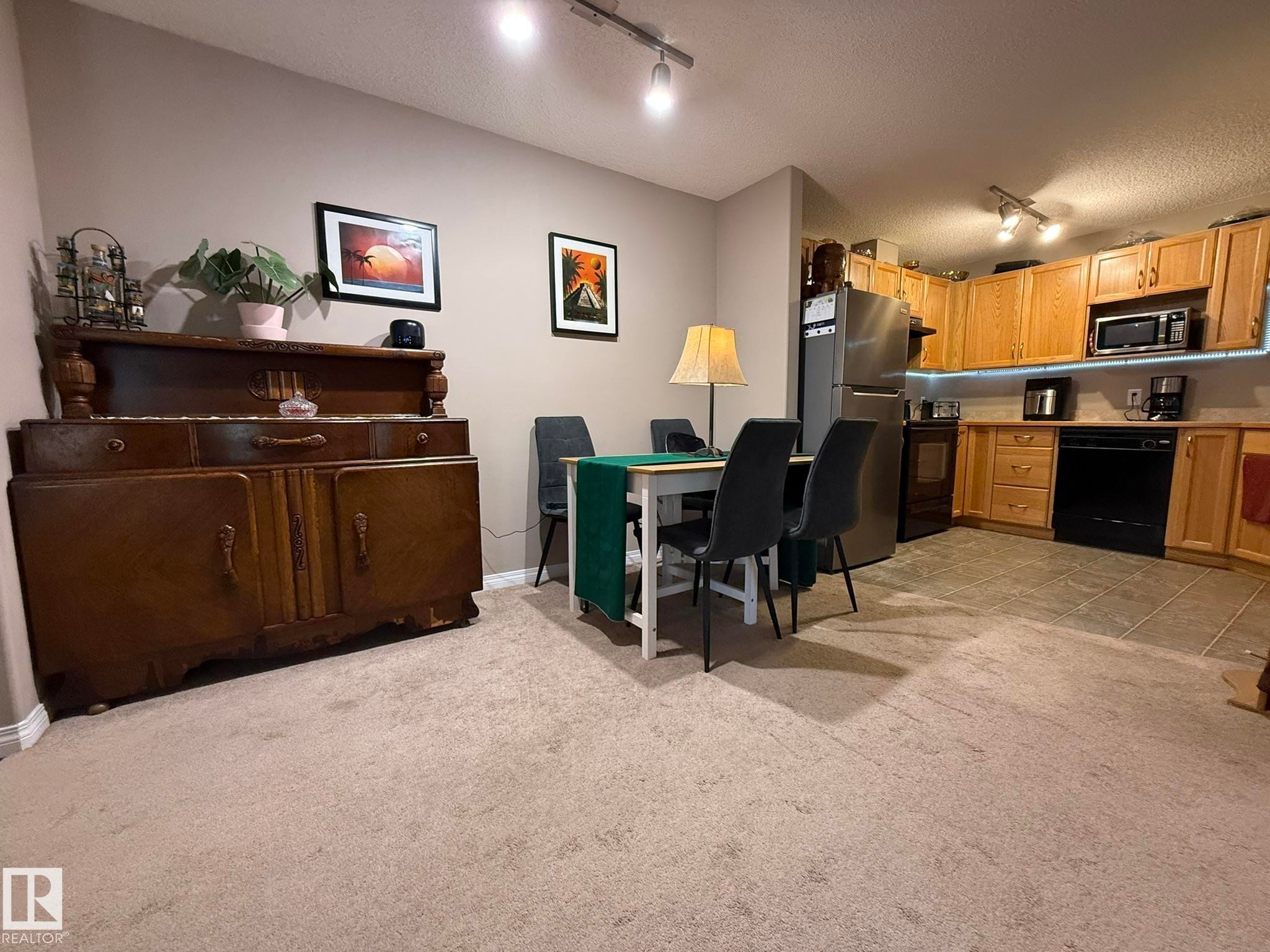 Open-concept living space featuring neutral carpet flooring throughout the main area - 205 3425 19 Street, Edmonton, AB