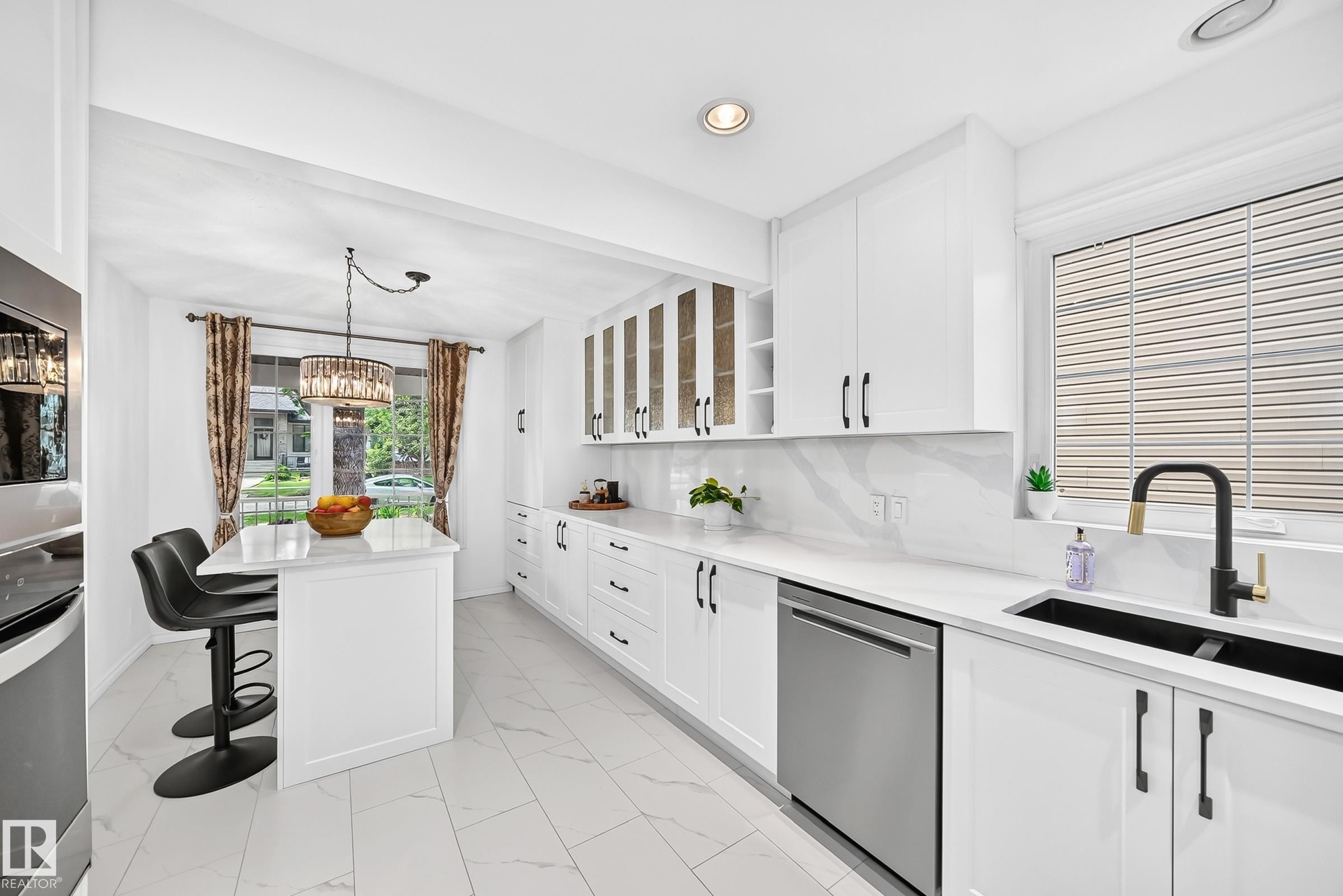 Contemporary kitchen featuring white cabinetry with black hardware, stainless steel dishwasher, black double basin sink with matte black faucet, and white countertops with a matching backsplash - 10323 138 Street Nw, Edmonton, AB - Indoor Photo Showing Kitchen With Double Sink