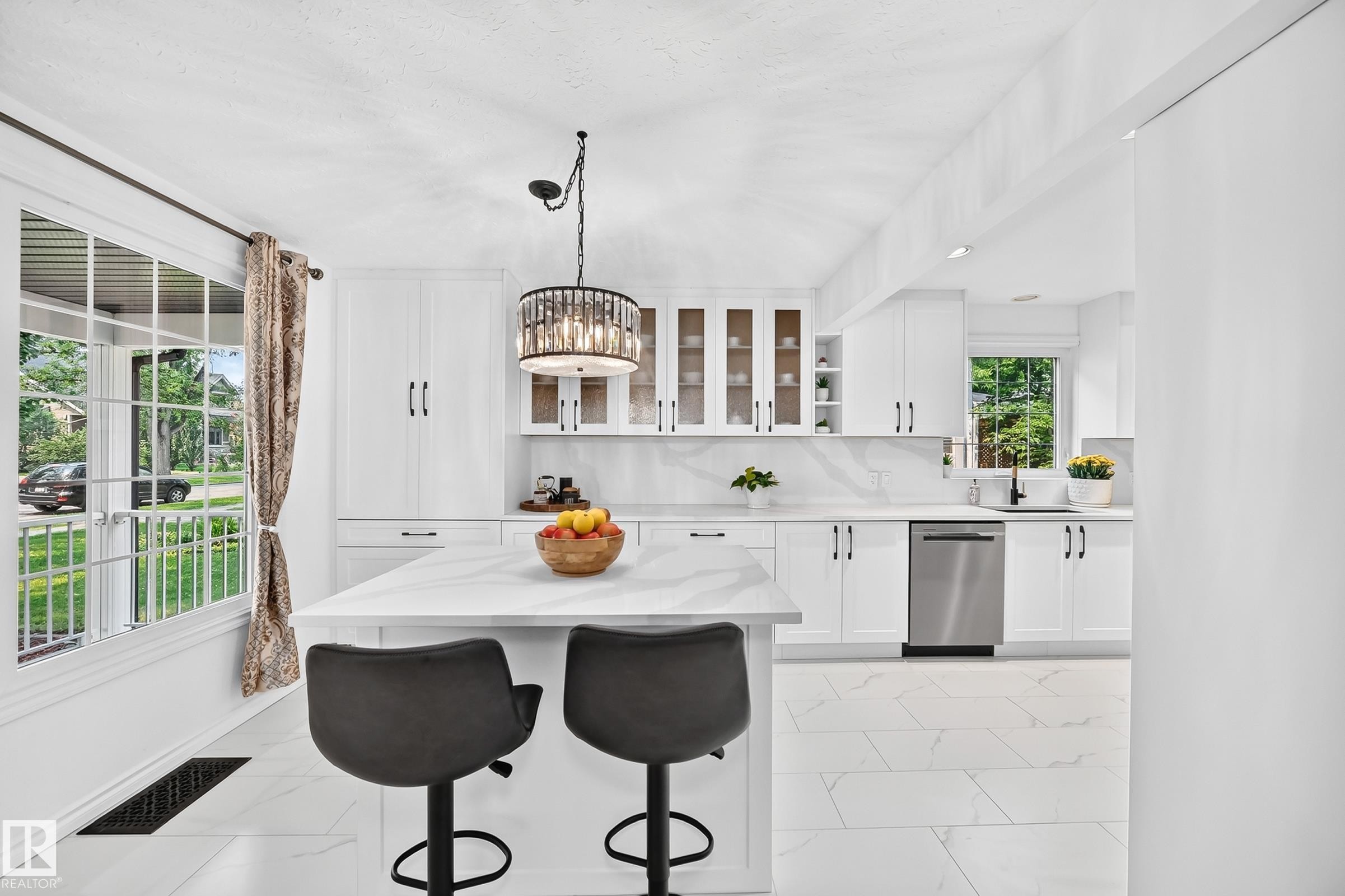 Bright kitchen featuring white shaker cabinetry, stainless steel dishwasher, and a center island with countertop seating - 10323 138 Street Nw, Edmonton, AB - Indoor