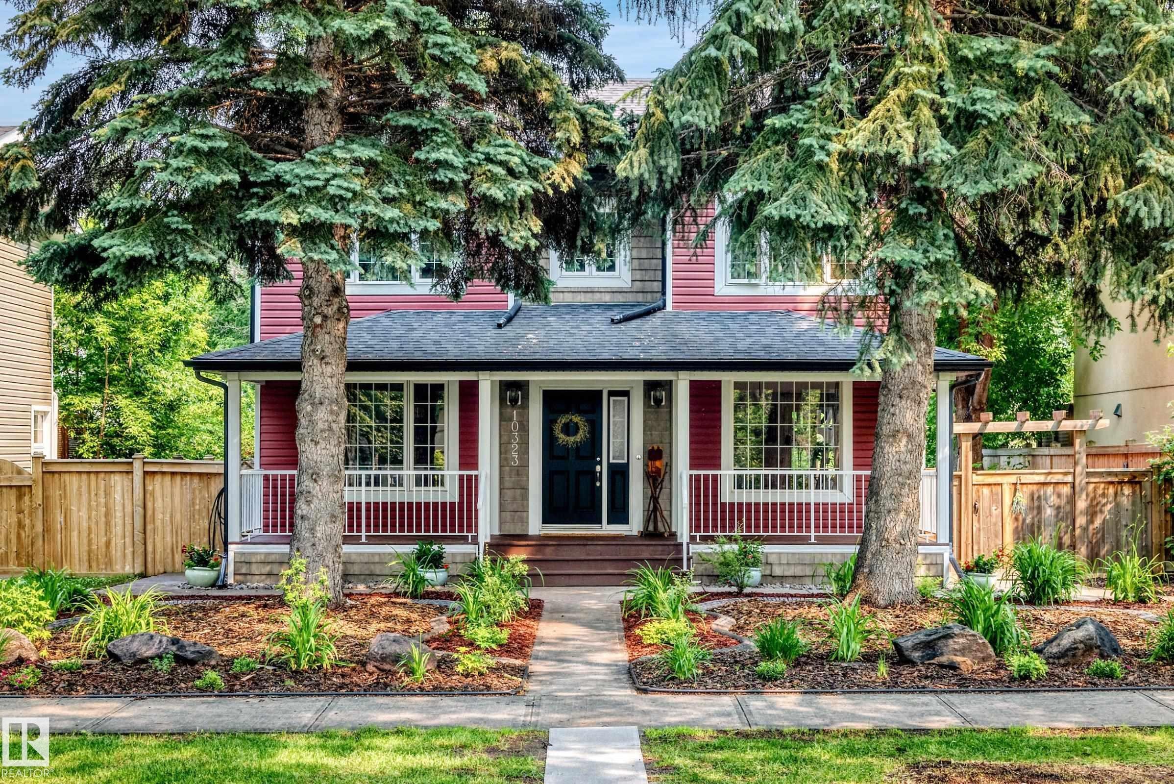 Red siding exterior with white trim, a covered porch, and a dark entry door - 10323 138 Street Nw, Edmonton, AB - Outdoor With Deck Patio Veranda With Facade