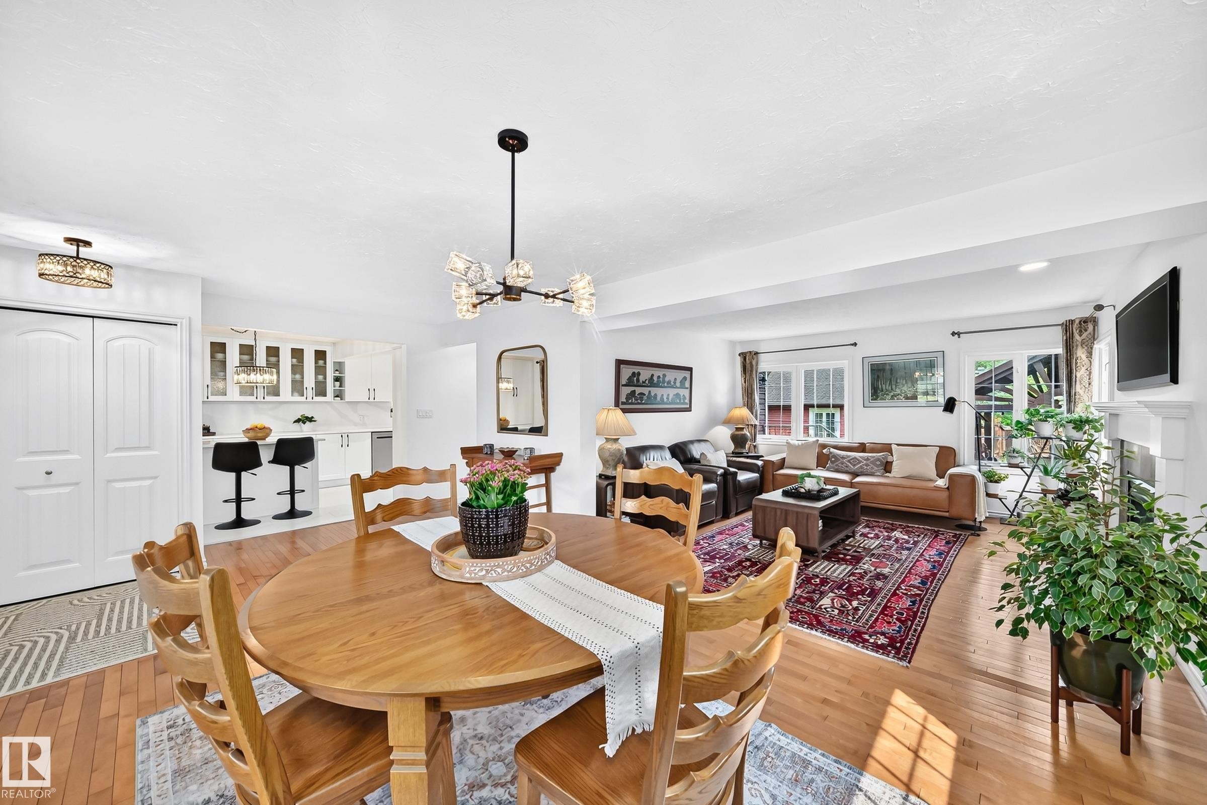 Open-concept living area featuring wood-finish flooring, a contemporary chandelier, a white fireplace mantel, and recessed lighting - 10323 138 Street Nw, Edmonton, AB - Indoor Photo Showing Dining Room