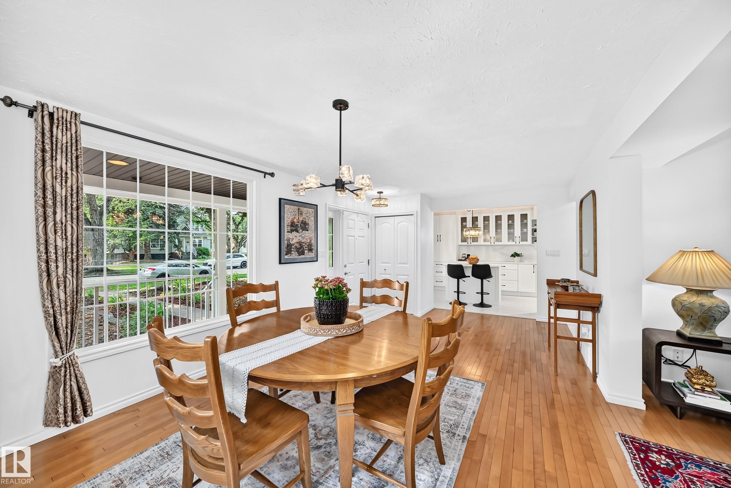 Dining area featuring wood-finish flooring, a contemporary chandelier, and a large multi-pane window - 10323 138 Street Nw, Edmonton, AB - Indoor Photo Showing Dining Room