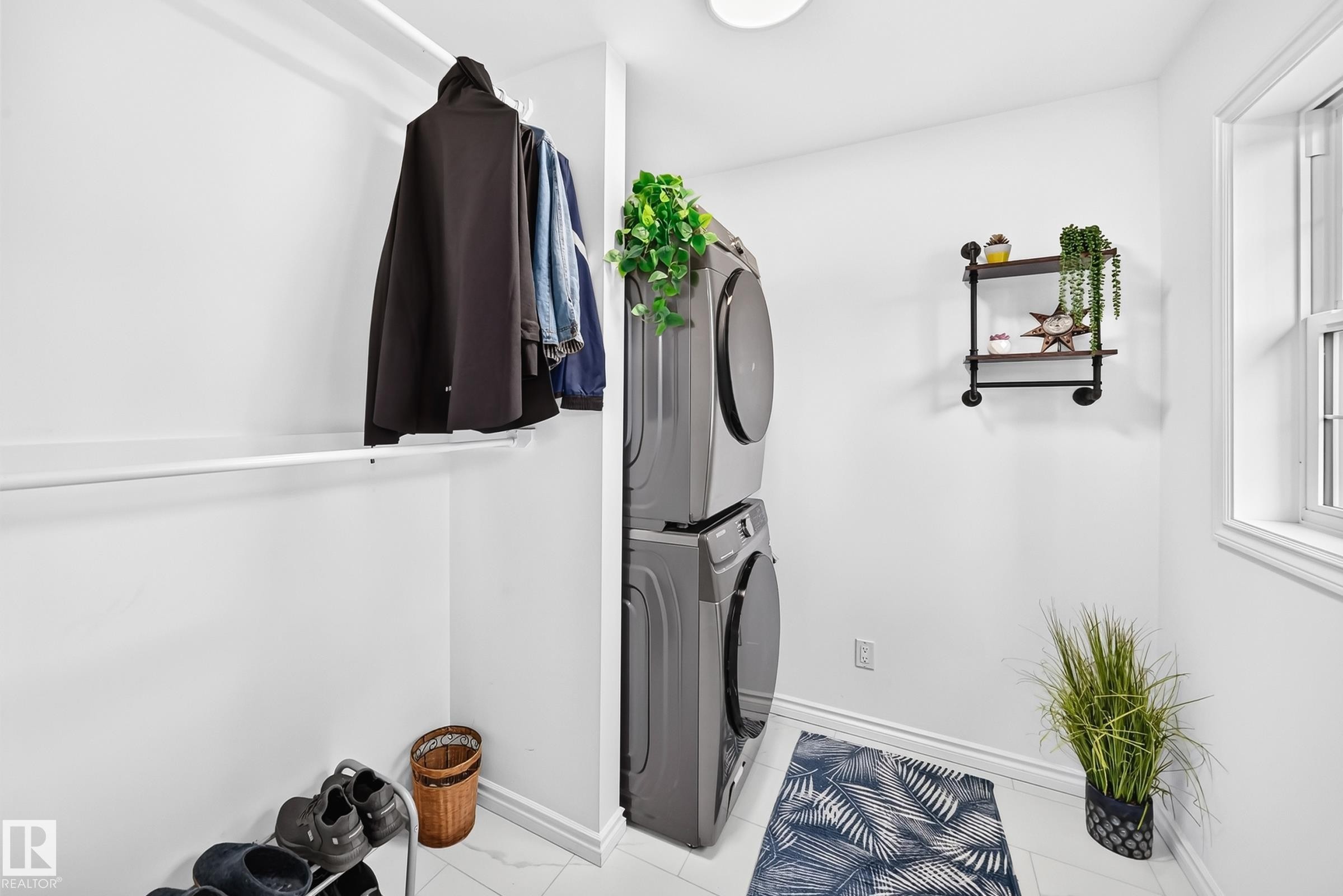 Dedicated laundry area featuring stacked appliances, a bright window, and white wall finishes - 10323 138 Street Nw, Edmonton, AB - Indoor