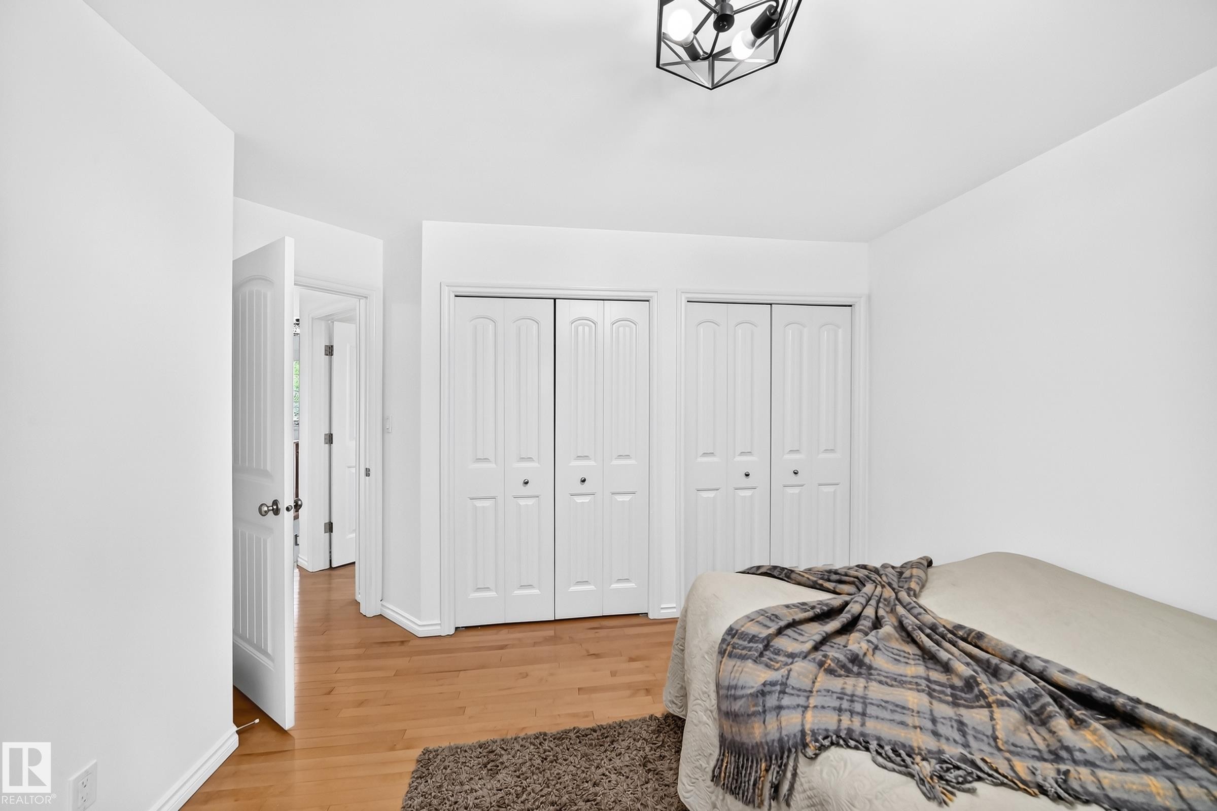 Bedroom with wood-finish flooring and a geometric ceiling light fixture - 10323 138 Street Nw, Edmonton, AB - Indoor Photo Showing Bedroom