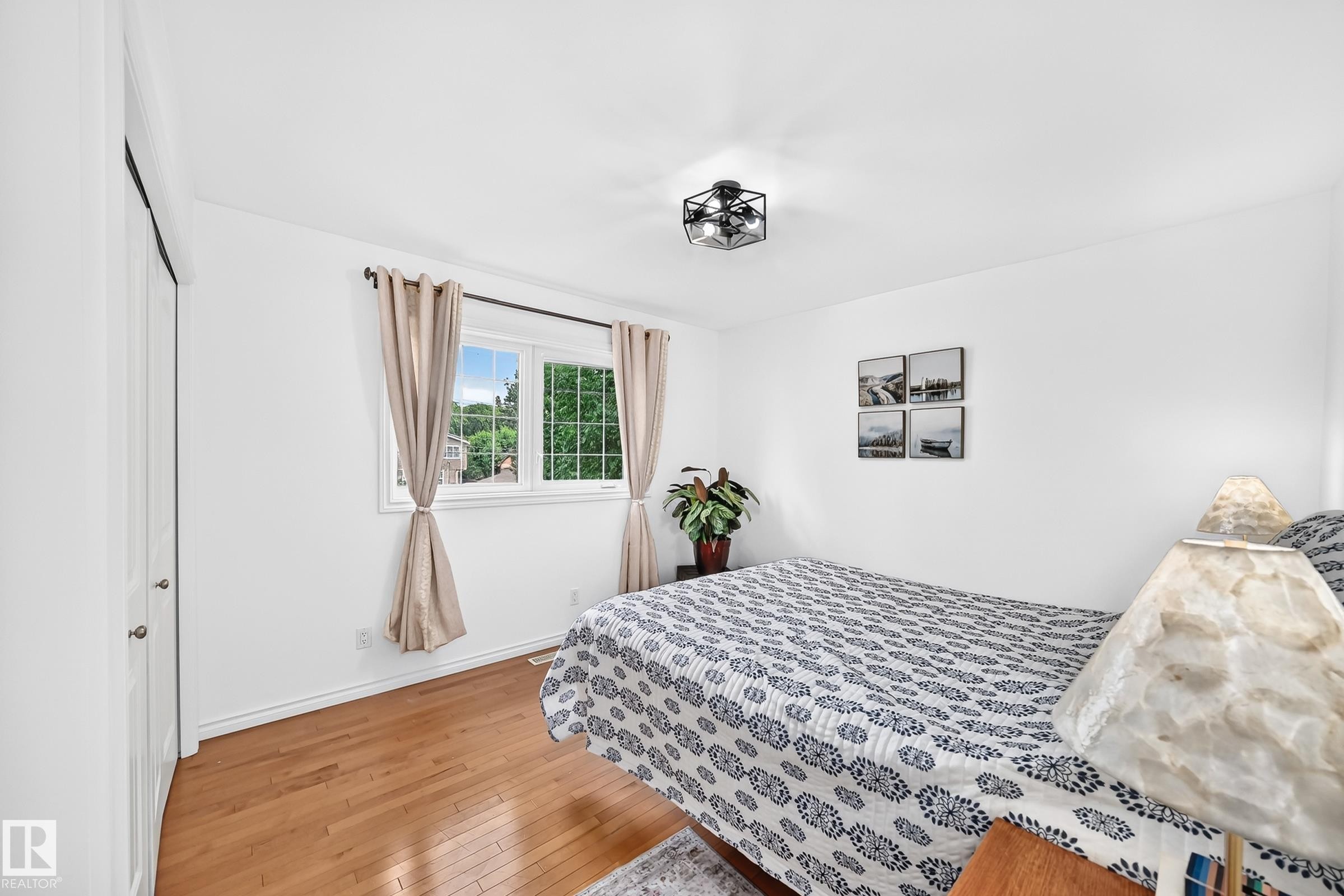White walls with wood-finish flooring, featuring a window with natural light and a contemporary ceiling fixture - 10323 138 Street Nw, Edmonton, AB - Indoor Photo Showing Bedroom