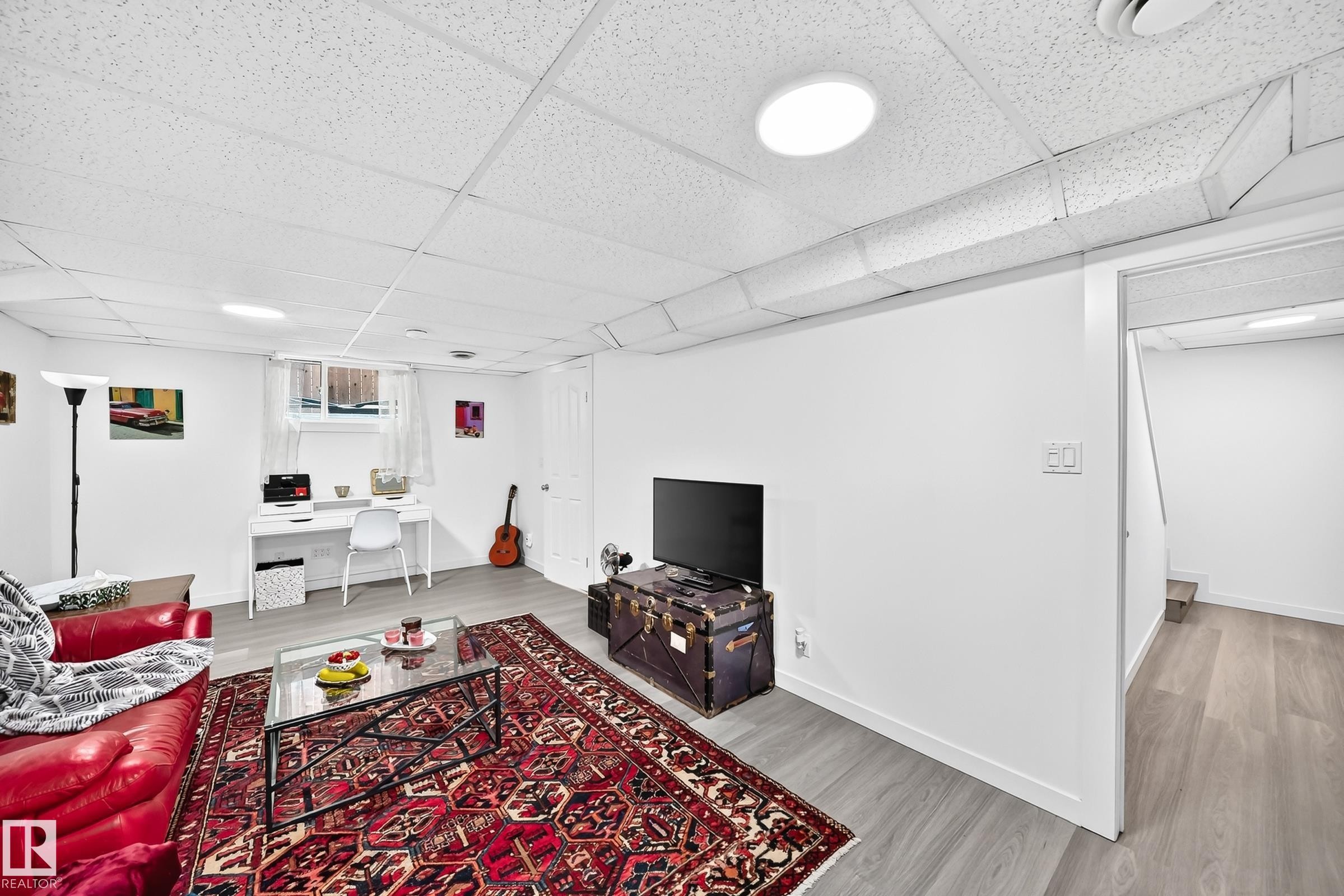 Finished lower level featuring light wood-finish flooring, white walls, and a drop ceiling with recessed lighting - 10323 138 Street Nw, Edmonton, AB - Indoor