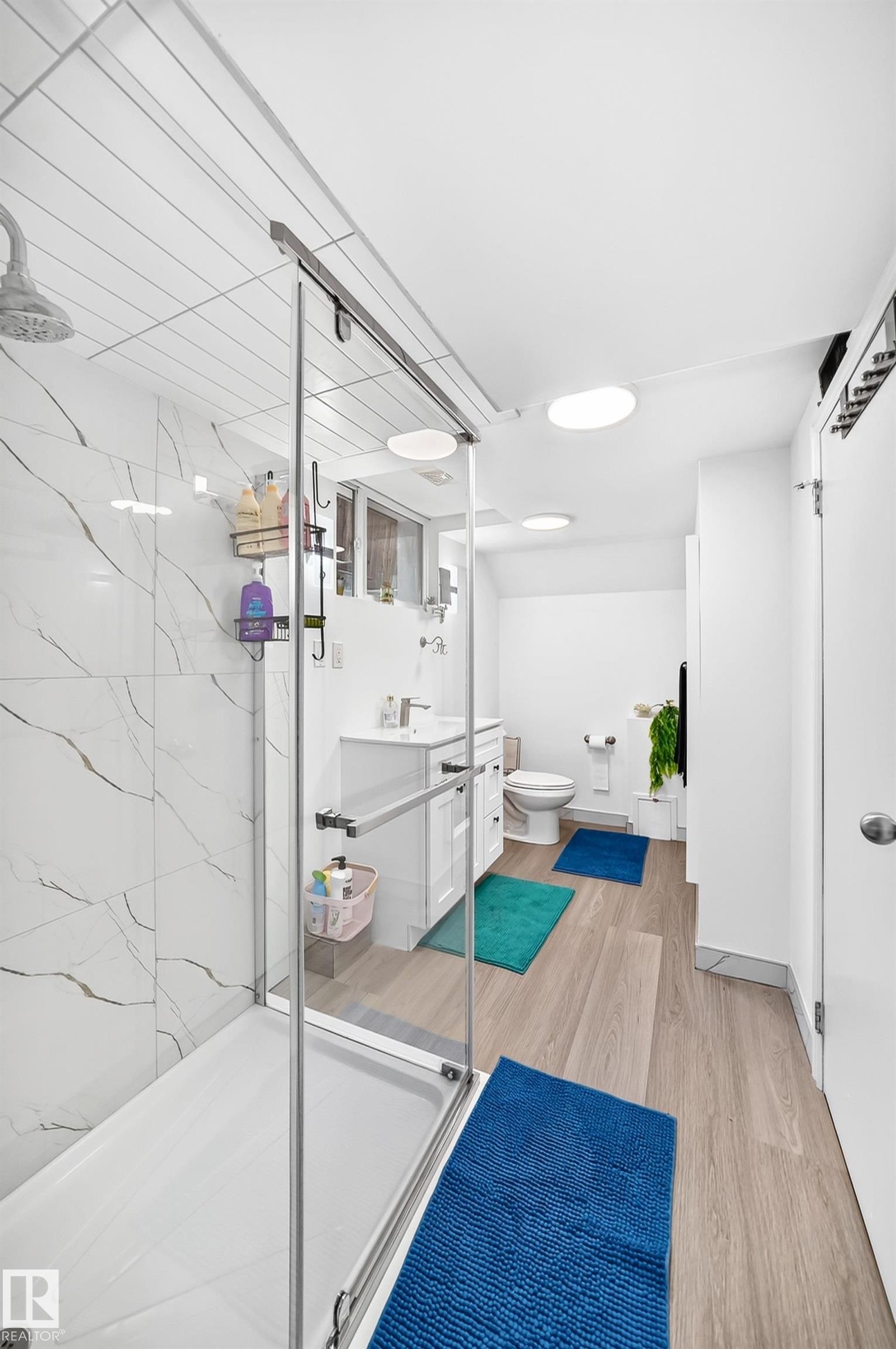 Contemporary bathroom with a glass-enclosed shower featuring marble-look tile, wood-finish flooring, and recessed lighting - 10323 138 Street Nw, Edmonton, AB - Indoor