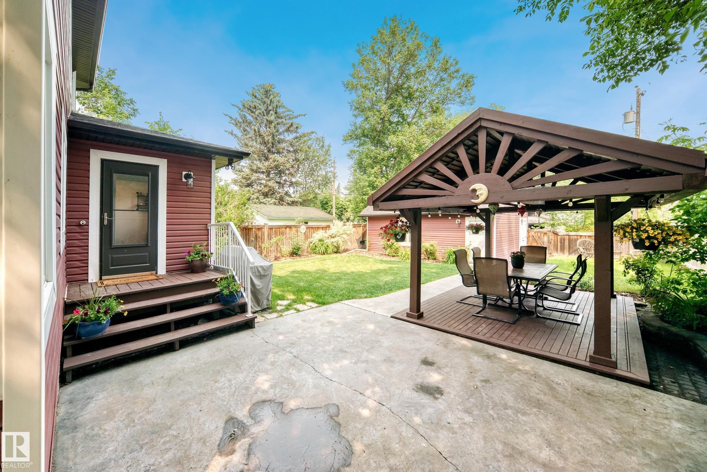 Expansive stamped concrete patio featuring a covered pergola with a wood-finish deck - 10323 138 Street Nw, Edmonton, AB - Outdoor With Deck Patio Veranda