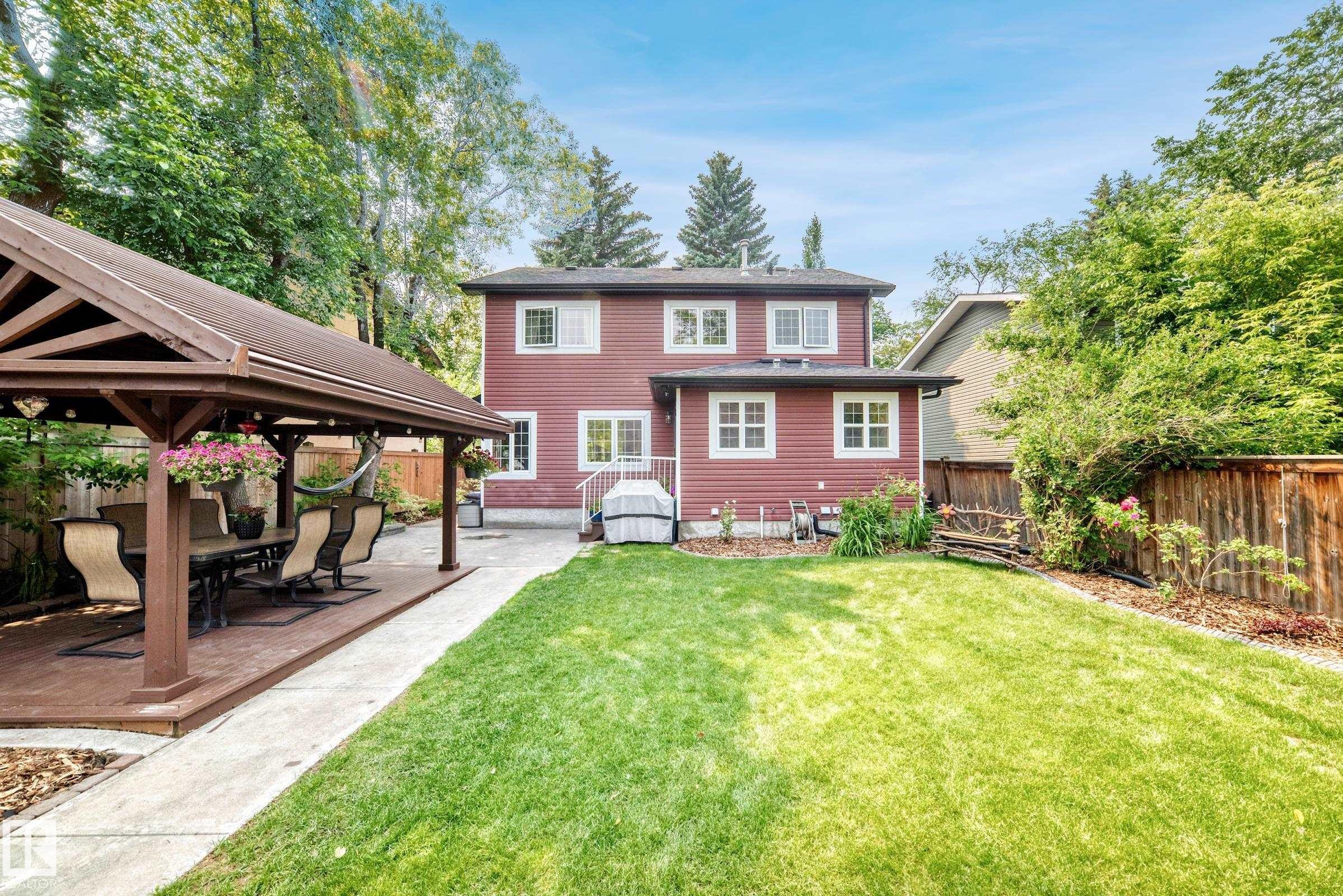 Expansive backyard featuring a green lawn, wood fence, and mature trees - 10323 138 Street Nw, Edmonton, AB - Outdoor