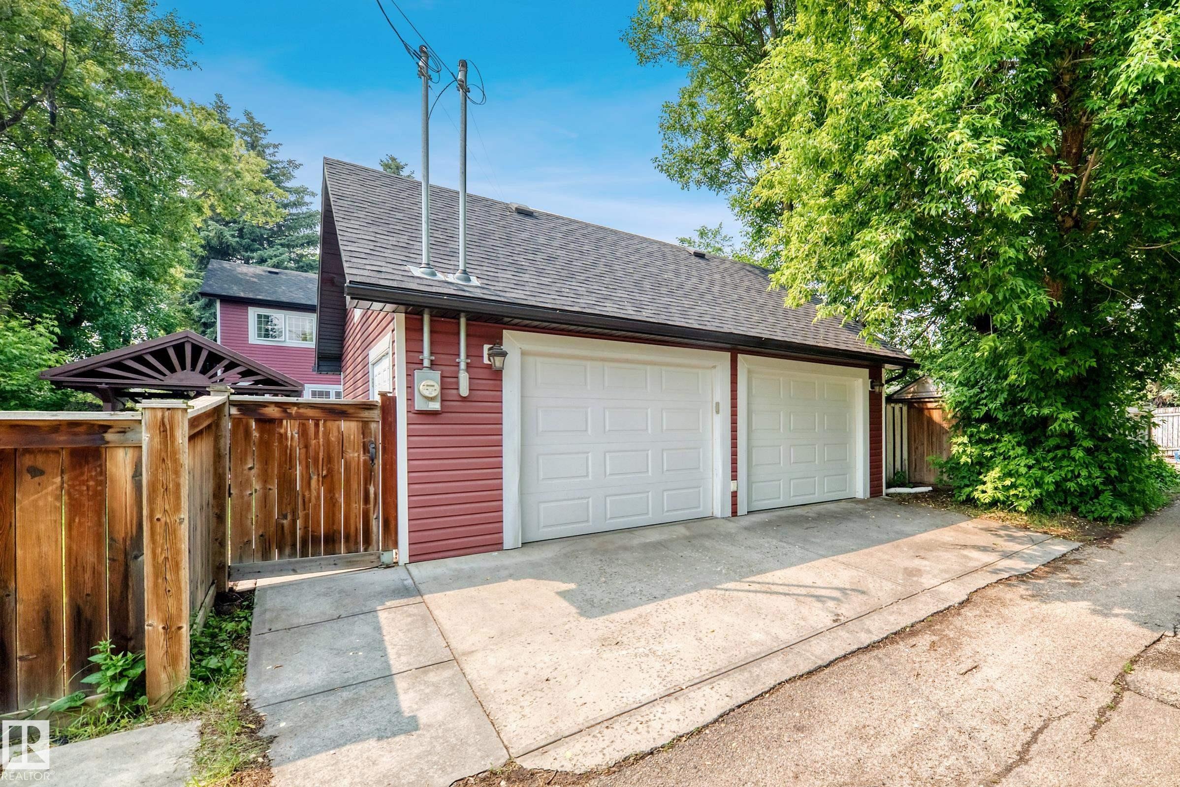 Two-car garage featuring white paneled doors, red siding, and a dark shingle roof - 10323 138 Street Nw, Edmonton, AB - Outdoor
