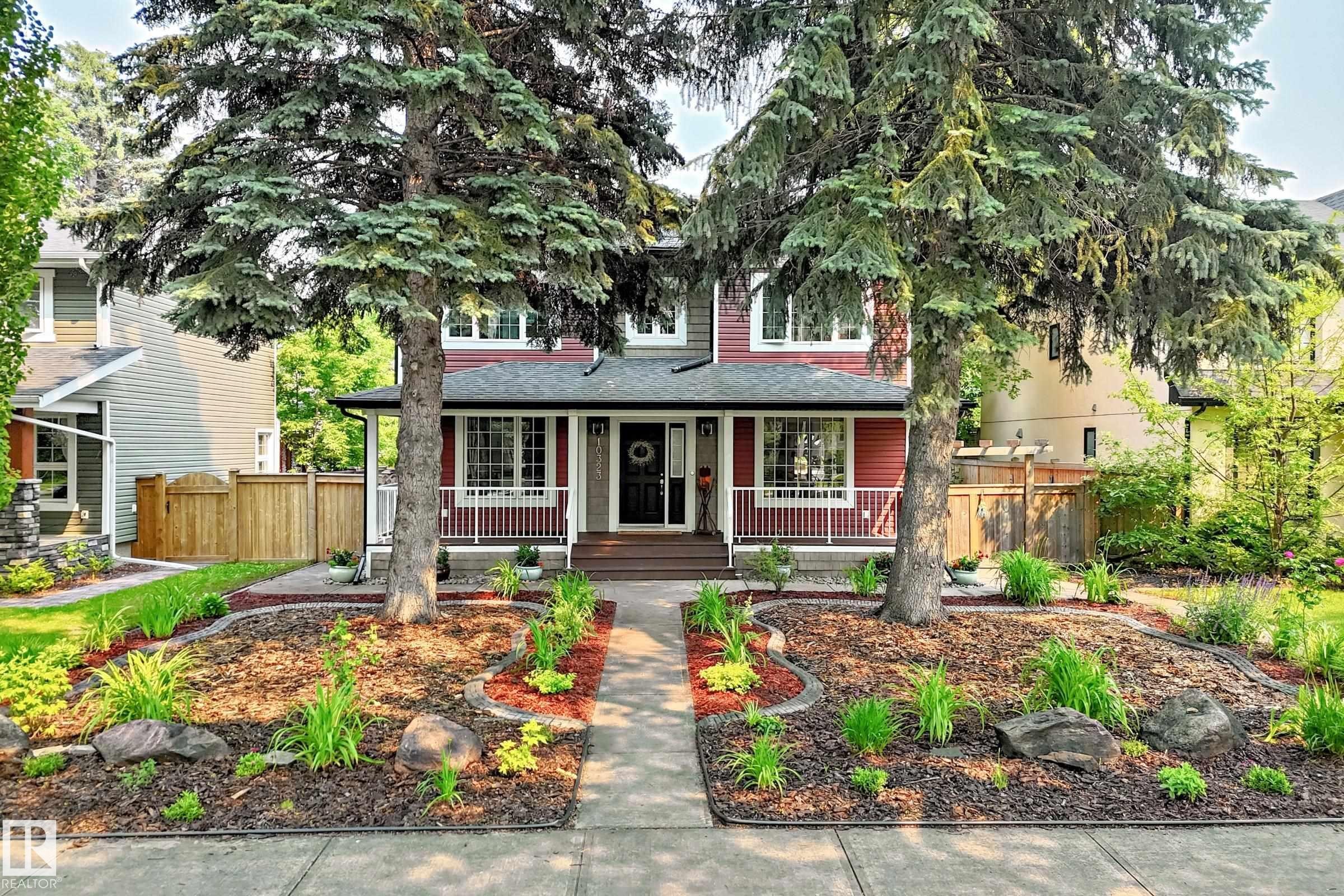 Red siding exterior with white trim and a covered front porch featuring white railings - 10323 138 Street Nw, Edmonton, AB - Outdoor With Deck Patio Veranda