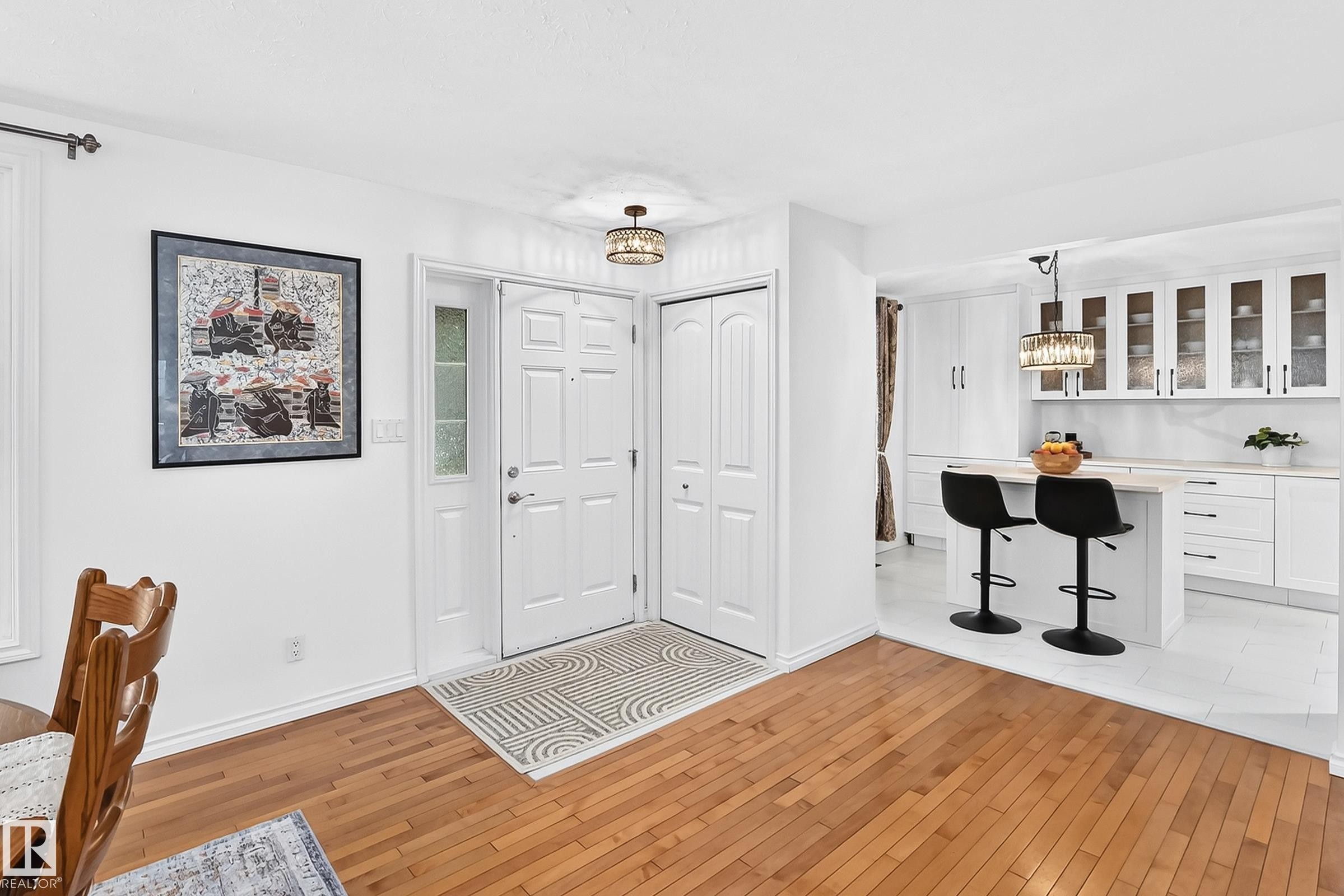 Entryway featuring wood-finish flooring, a white paneled door with a sidelight, and an overhead drum chandelier - 10323 138 Street Nw, Edmonton, AB - Indoor Photo Showing Other Room