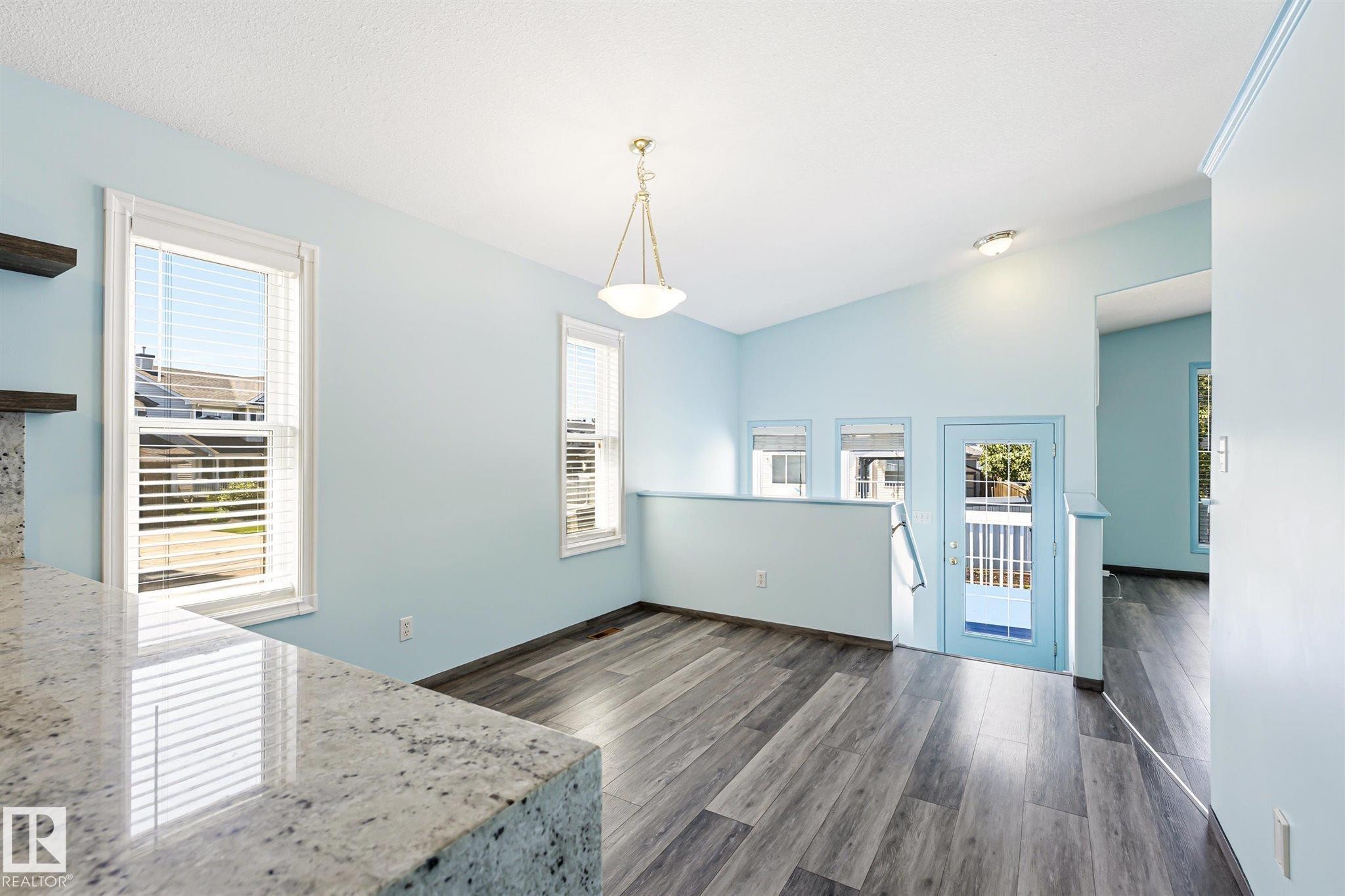 Open-concept living area featuring wood-finish flooring, a vaulted ceiling, and multiple windows with blinds - 14908 137 Street Nw, Edmonton, AB - Indoor Photo Showing Other Room