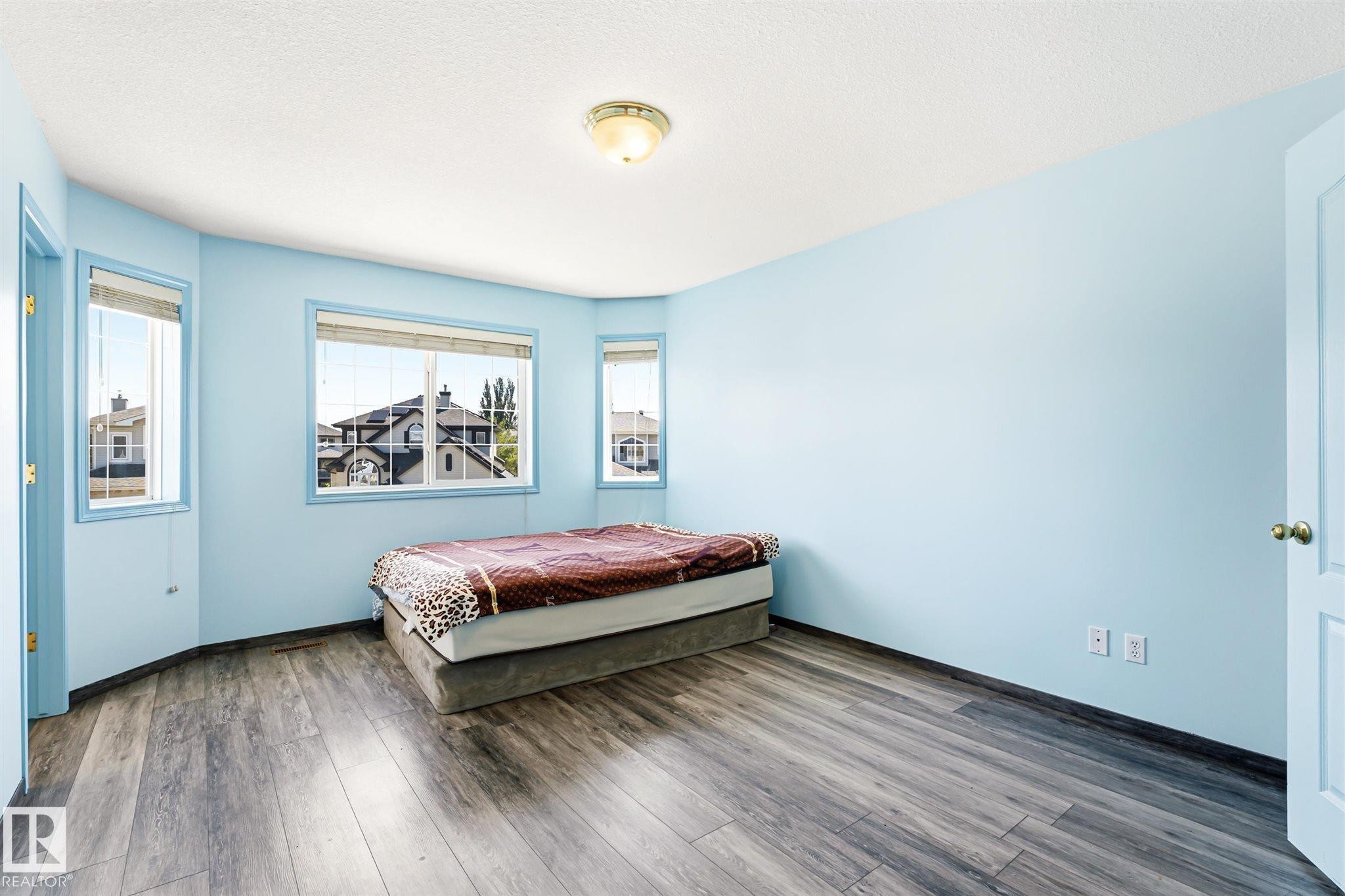 Room with multi-pane windows, wood-finish flooring, a flush-mount ceiling light fixture, and a light-colored door - 14908 137 Street Nw, Edmonton, AB - Indoor Photo Showing Bedroom