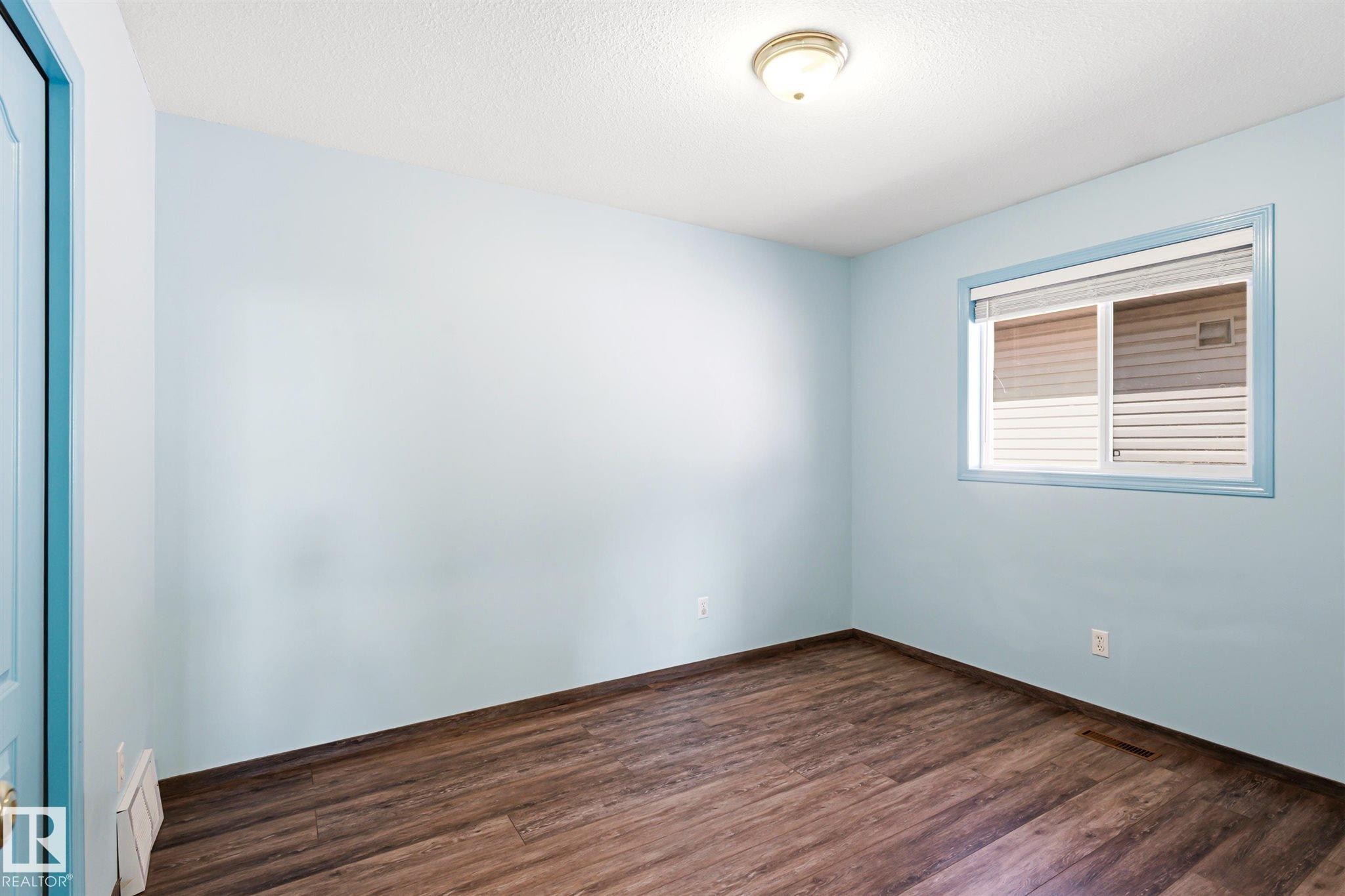 Room featuring wood-finish flooring, light blue walls, and a white ceiling - 14908 137 Street Nw, Edmonton, AB - Indoor Photo Showing Other Room