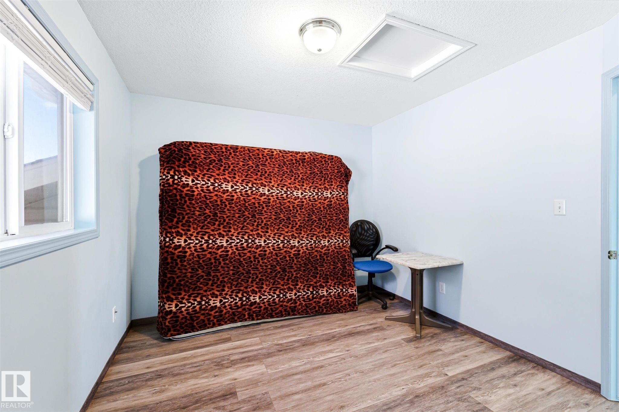 Interior room featuring wood-finish flooring, a white trim window, and light blue wall tones - 14908 137 Street Nw, Edmonton, AB - Indoor