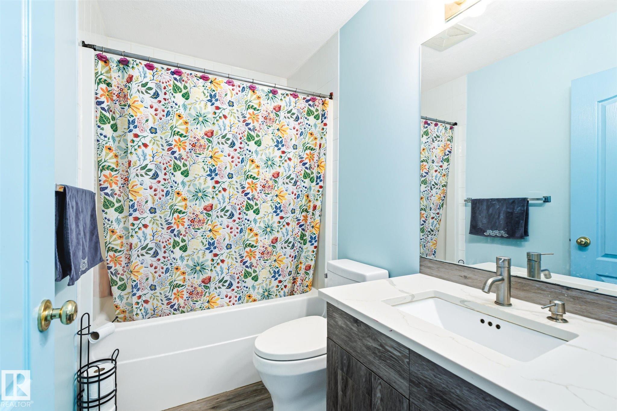 Full bathroom featuring a single vanity with an integrated sink, a white countertop, and wood-finish cabinetry - 14908 137 Street Nw, Edmonton, AB - Indoor Photo Showing Bathroom
