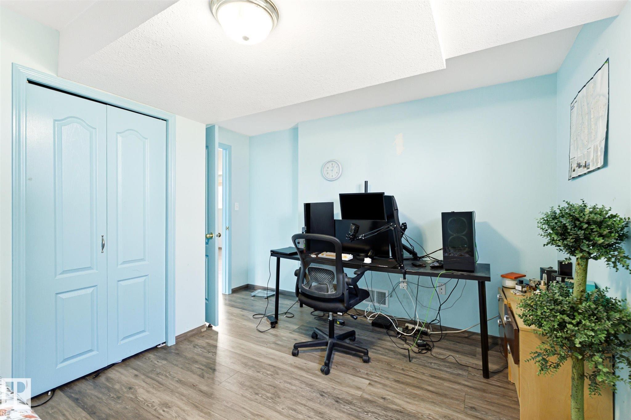 Room featuring wood-finish flooring, light blue walls, and a white textured ceiling - 14908 137 Street Nw, Edmonton, AB - Indoor Photo Showing Office