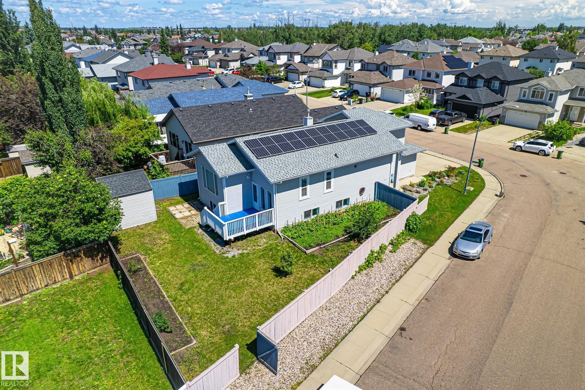 Residential property featuring light blue siding and a dark grey shingled roof with visible solar panels - 14908 137 Street Nw, Edmonton, AB - Outdoor With View