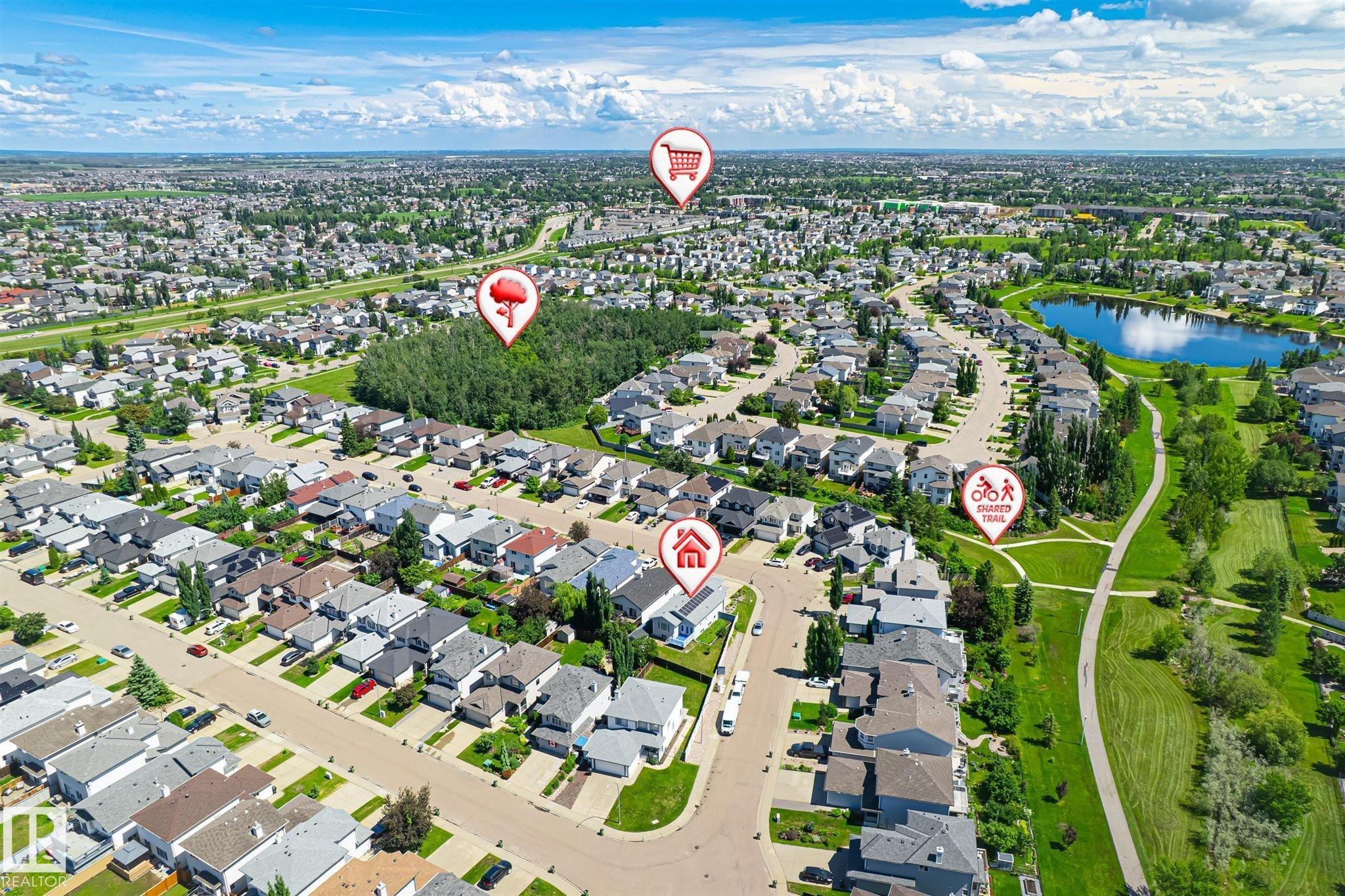 Aerial perspective showcasing a residential development with numerous single-family homes, a prominent body of water, and extensive green spaces - 14908 137 Street Nw, Edmonton, AB - Outdoor With View